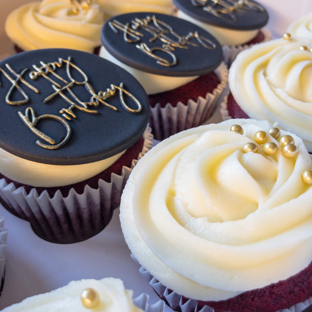 Classically elegant cupcakes with small gold balls and black fondant discs with Happy Birthday in gold topping the cupcakes.