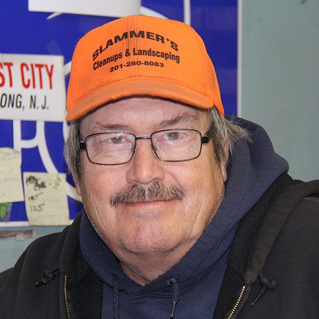 A man wearing an orange hat that says slammer 's cleanups & landscaping