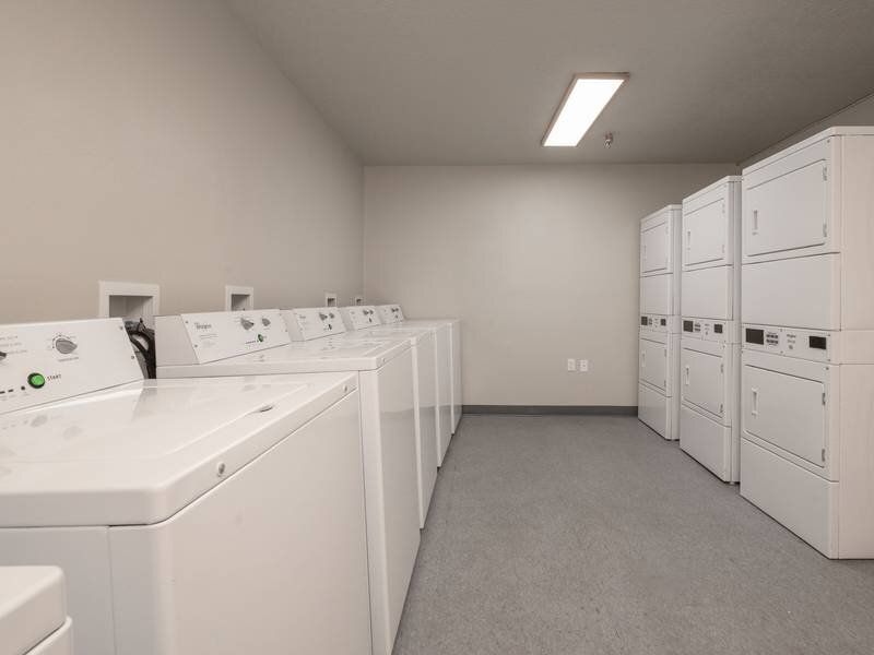 On-site communal laundry room with multiple washers and dryers along the walls at Santa Fe Suites in Santa Fe, NM.