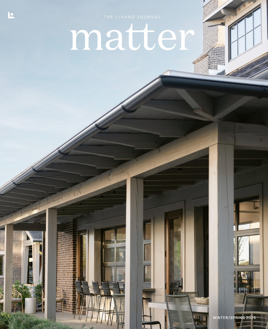 A modern building with a covered patio, outdoor chairs, and large windows under a clear sky, titled