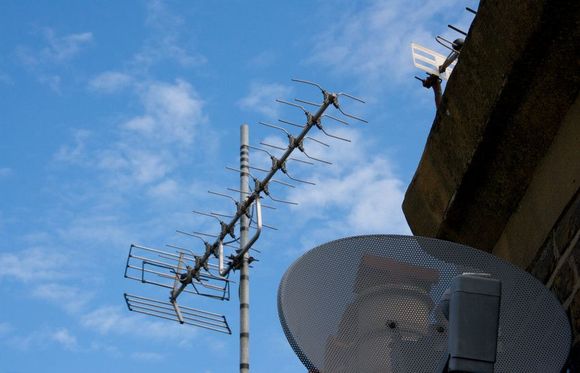 A satellite dish is attached to the side of a building.