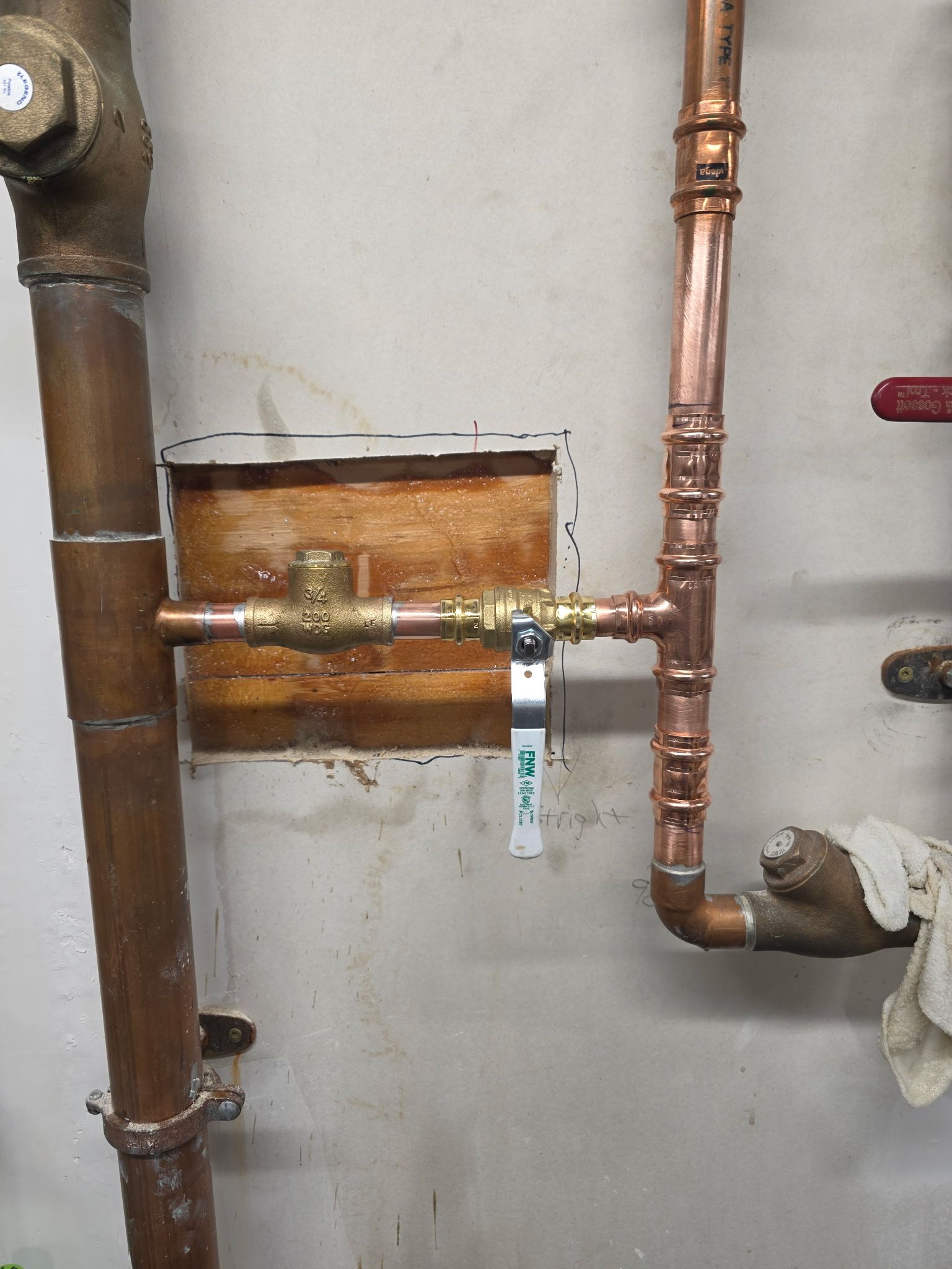 Plumbing with a brass valve, copper pipes, and white wall in an indoor setting.