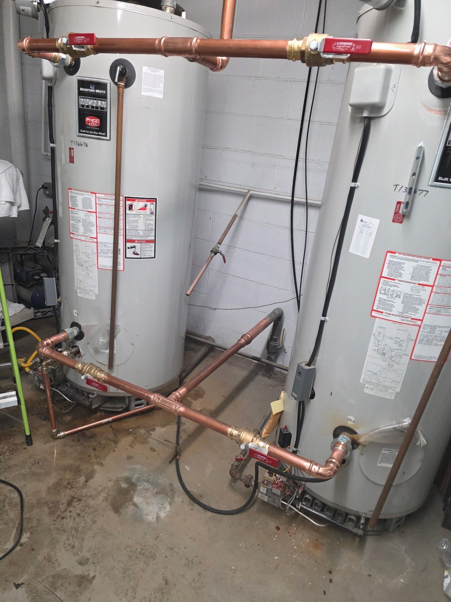 Two water heaters with copper piping in a basement.