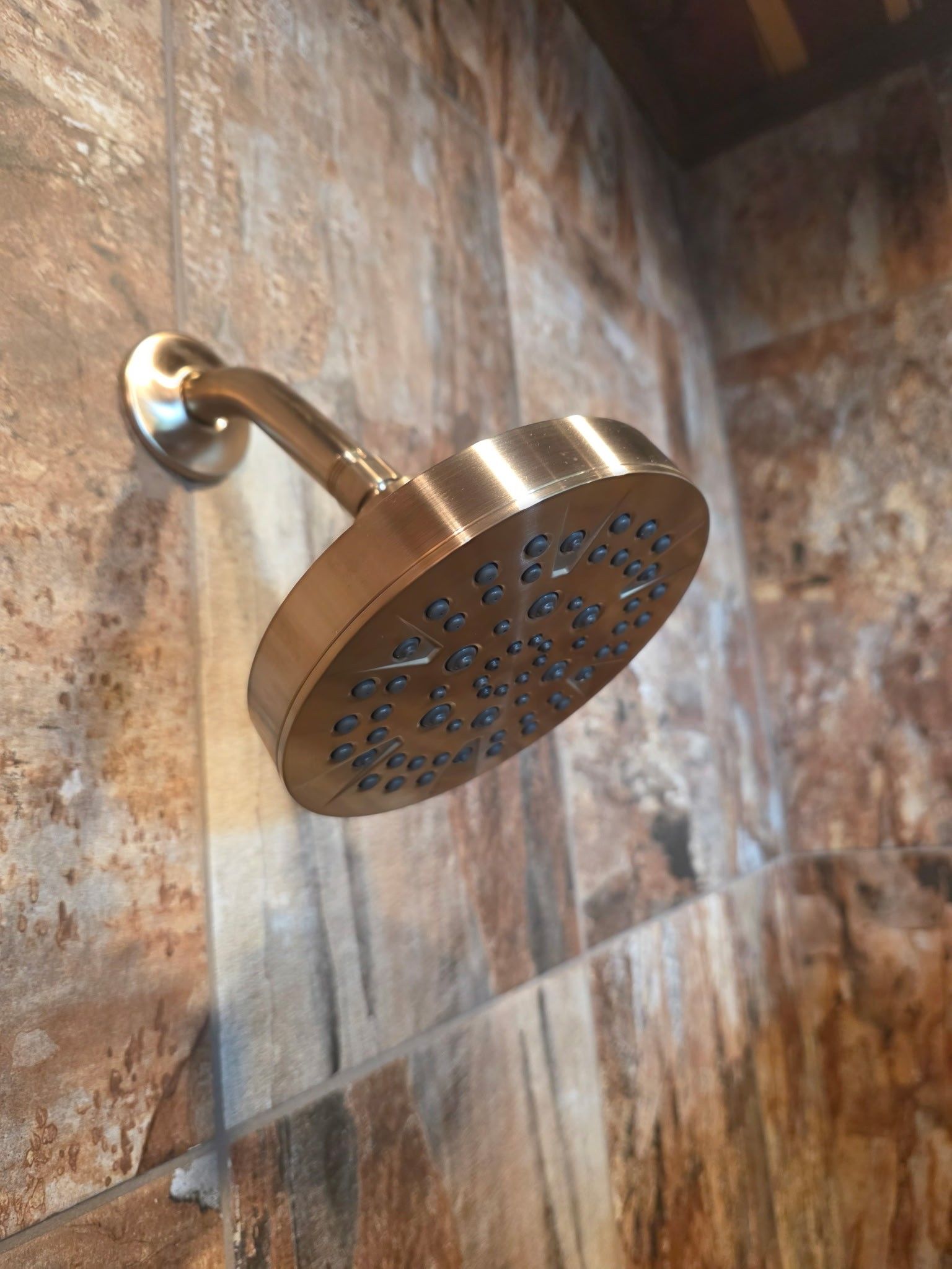 Gold showerhead on a tiled wall.
