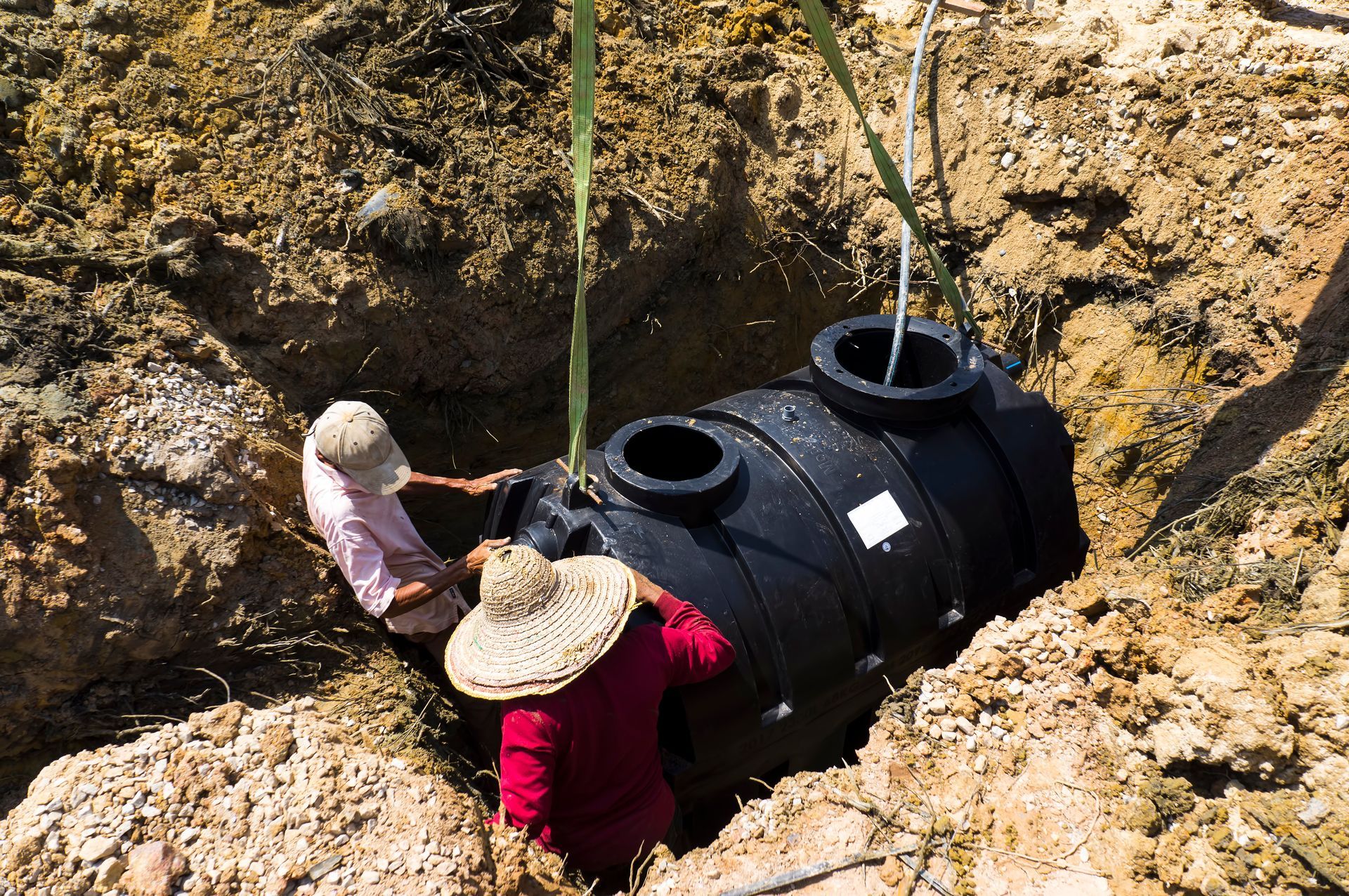 Technicians performing septic system installation with excavation and tank setup.