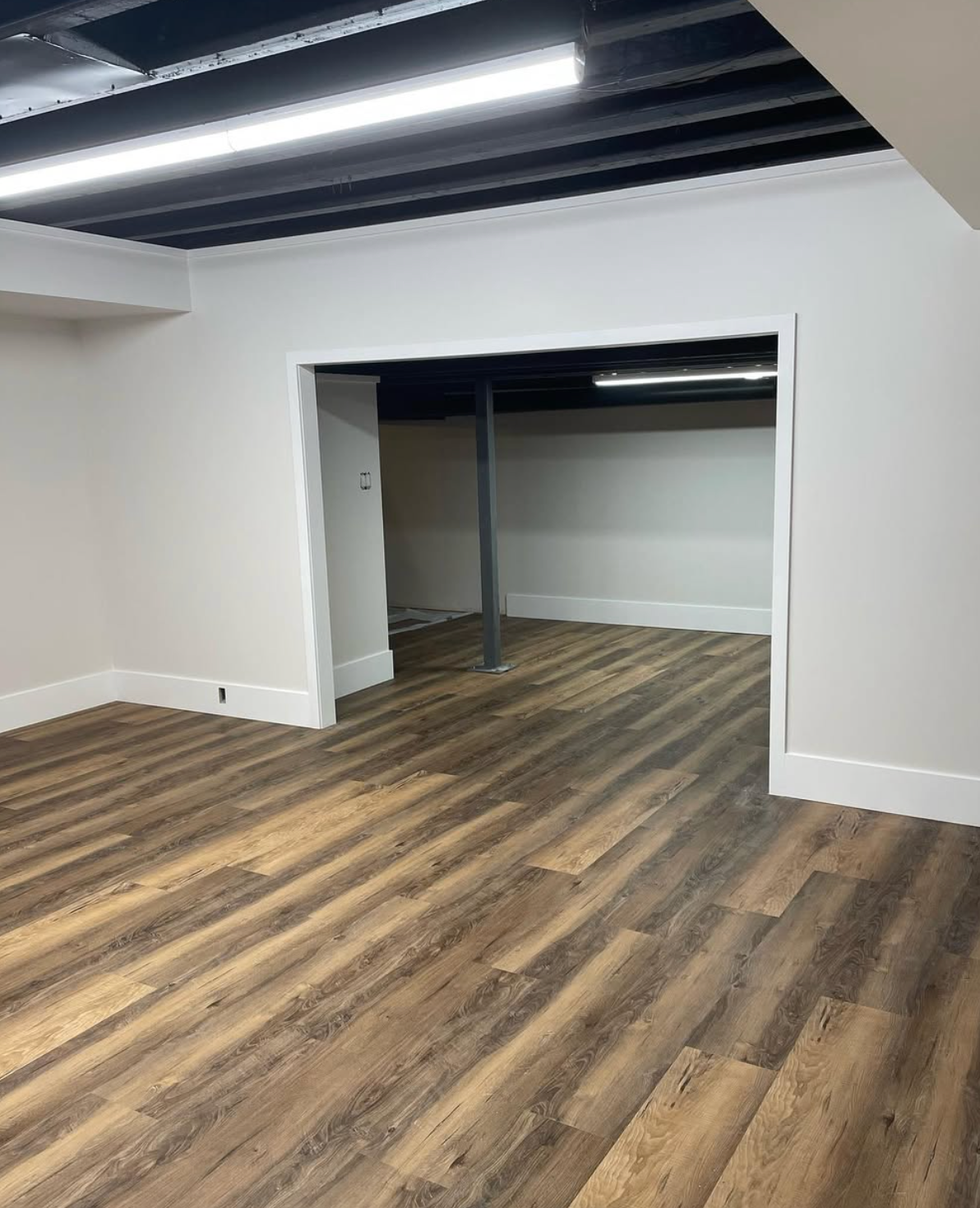 Empty room with wood-look flooring, white walls, and a recessed closet opening under a slanted ceiling.