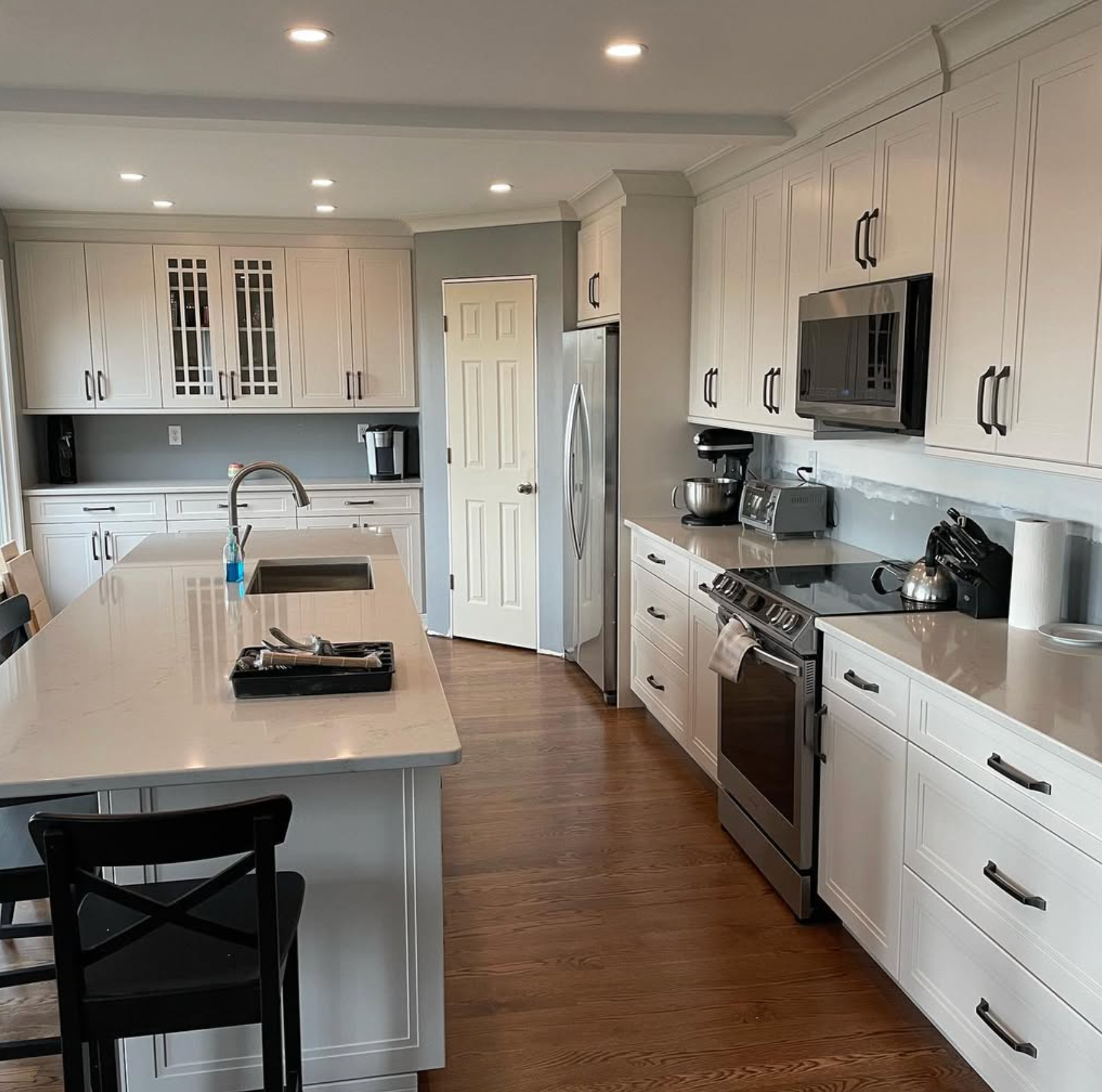 Bright white kitchen with island, stainless steel appliances, and wood floors