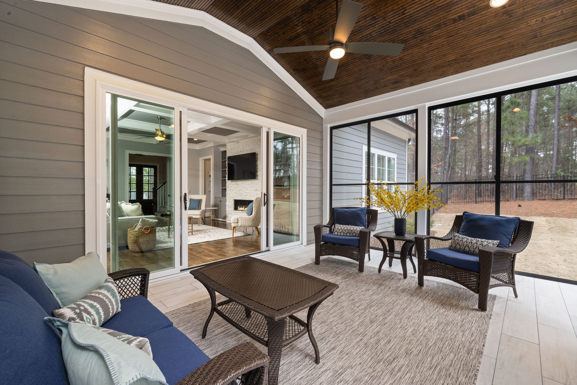 Covered patio with wicker seating, coffee table, and sliding glass doors to a living room