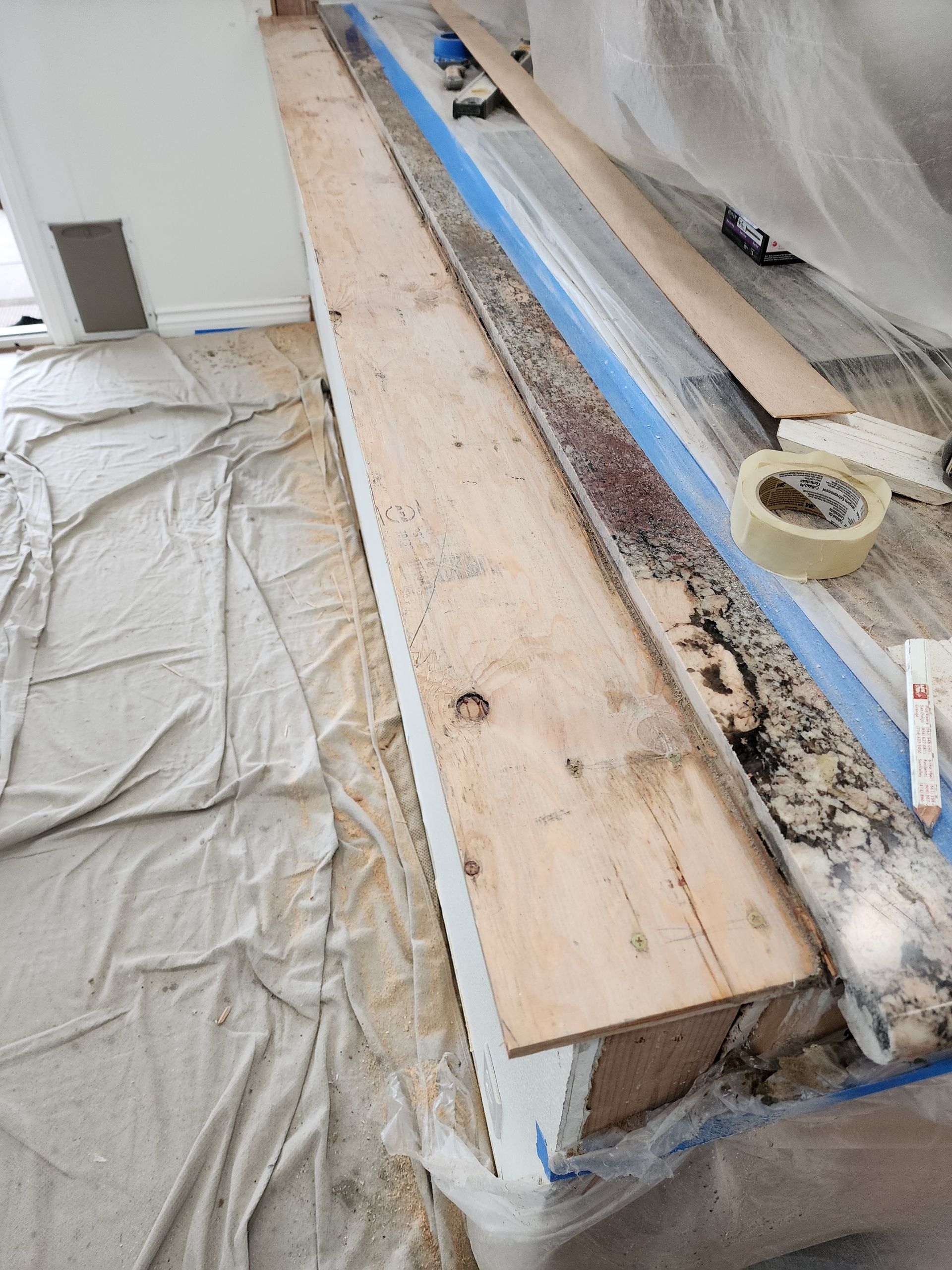 Wood beam on a counter, covered in debris, taped, and ready for work in a room under renovation.