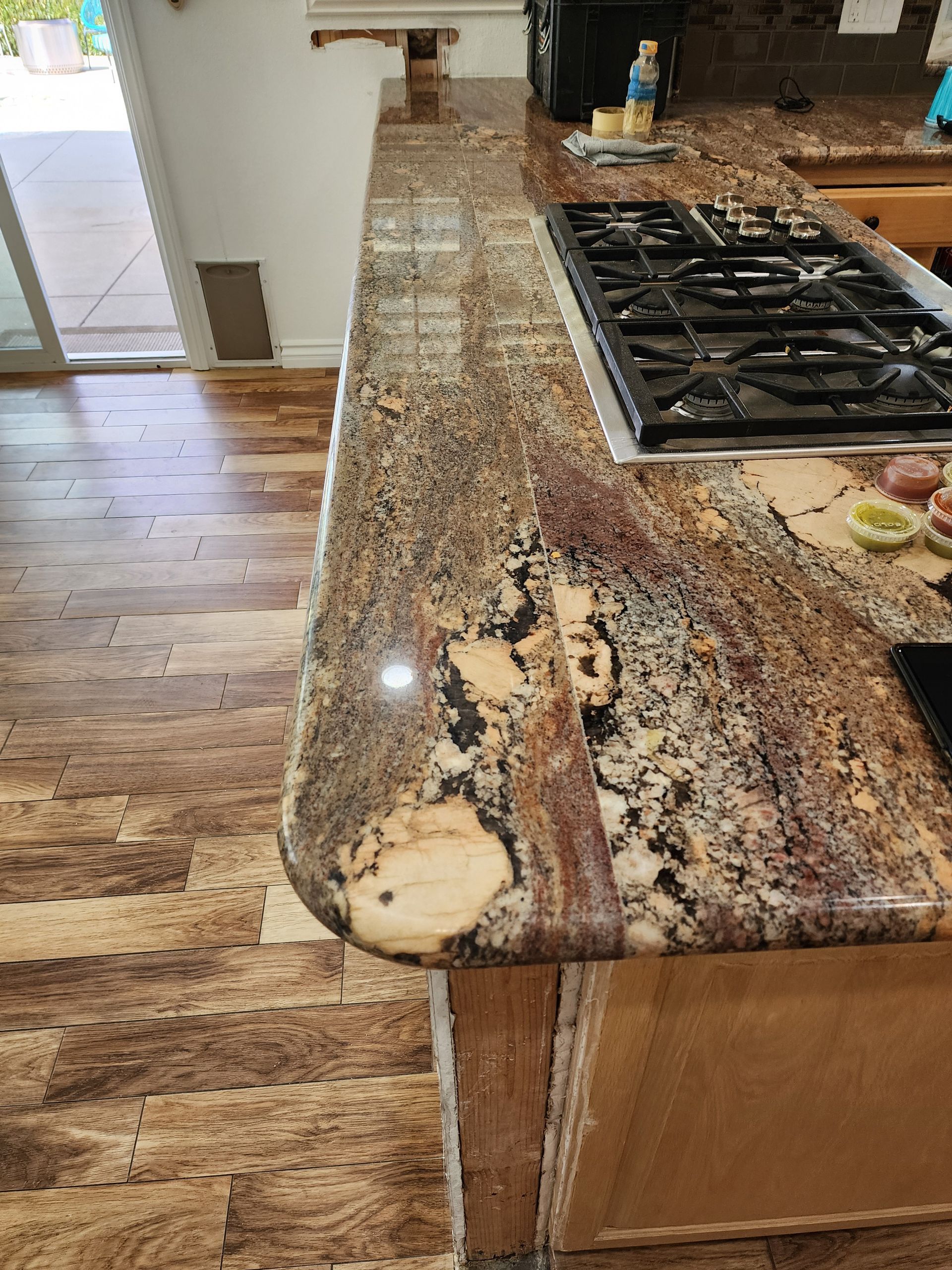 Granite countertop with a rounded edge next to a stove. Light and dark brown colors.