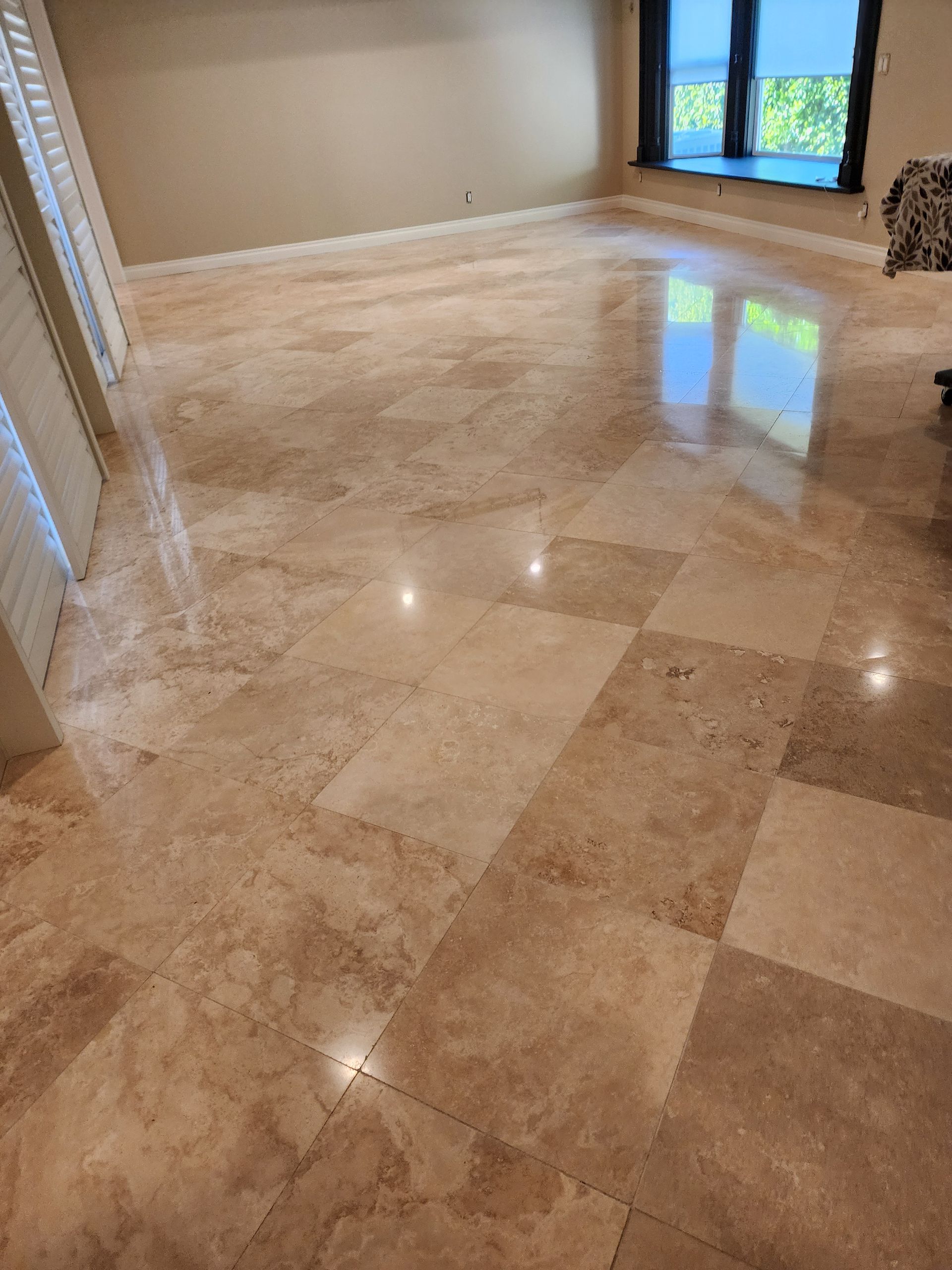 Polished beige tile floor reflecting light in a room with a window.