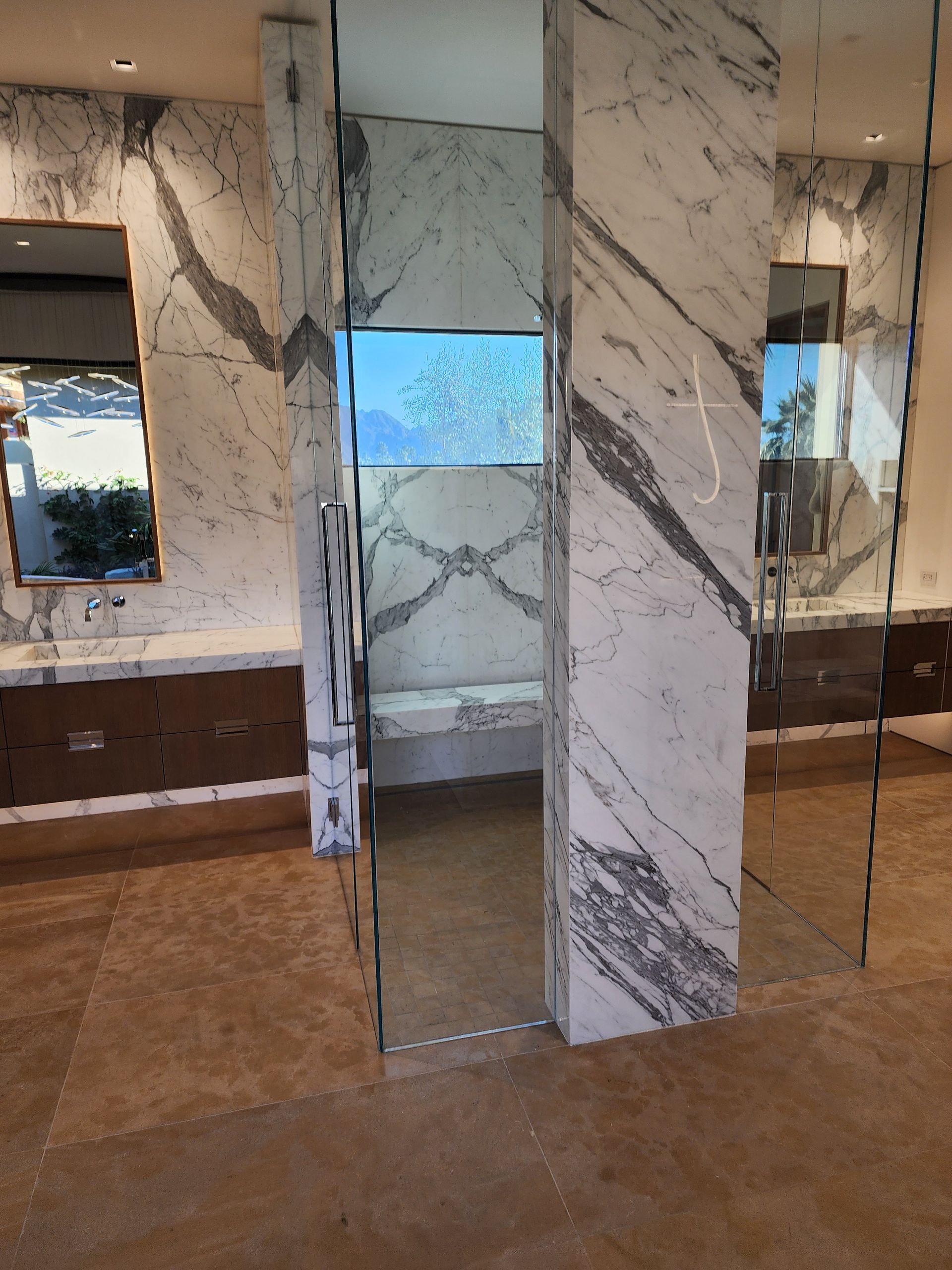 Luxurious bathroom with marble walls, glass shower, and beige floor.