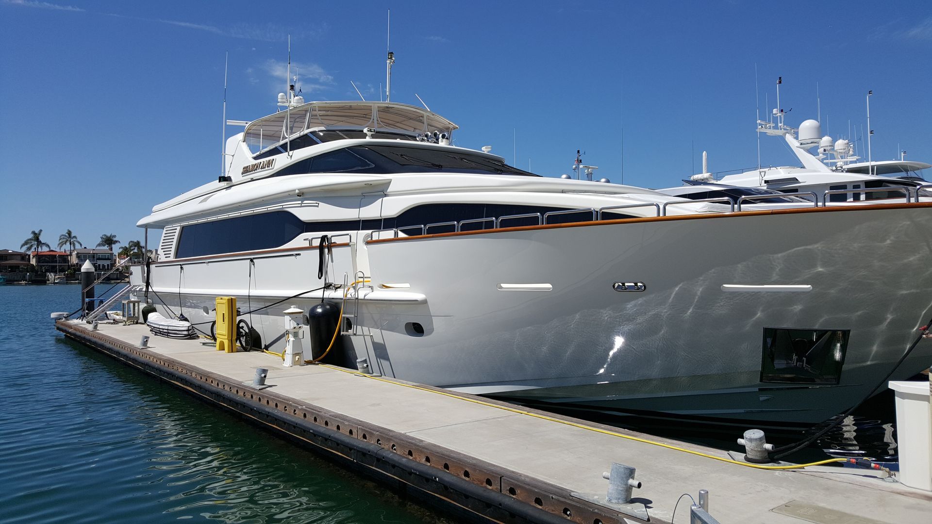 Large white yacht docked at a pier on a sunny day.