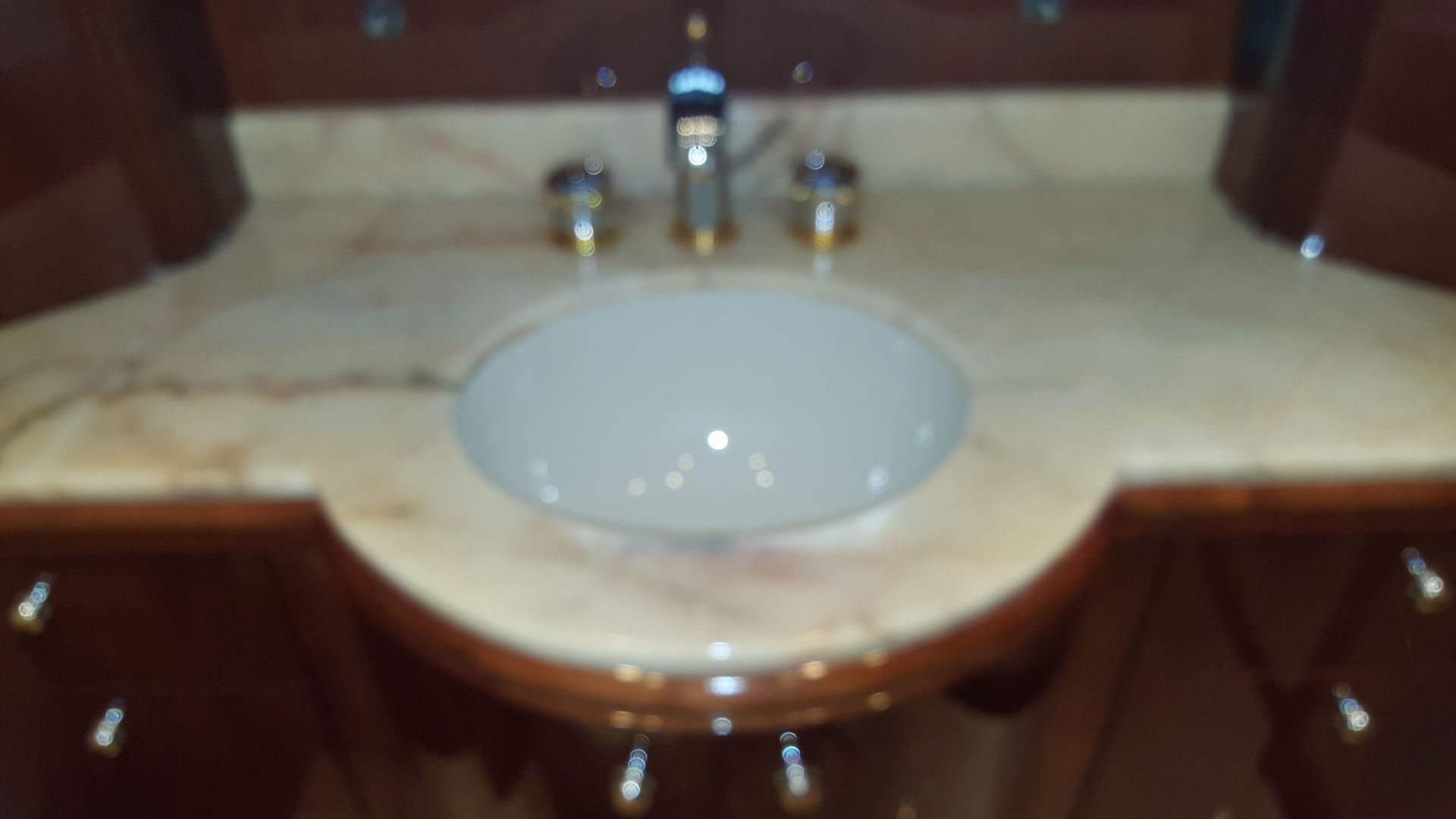 Bathroom sink with light marble countertop, dark wood cabinetry, and chrome faucet.