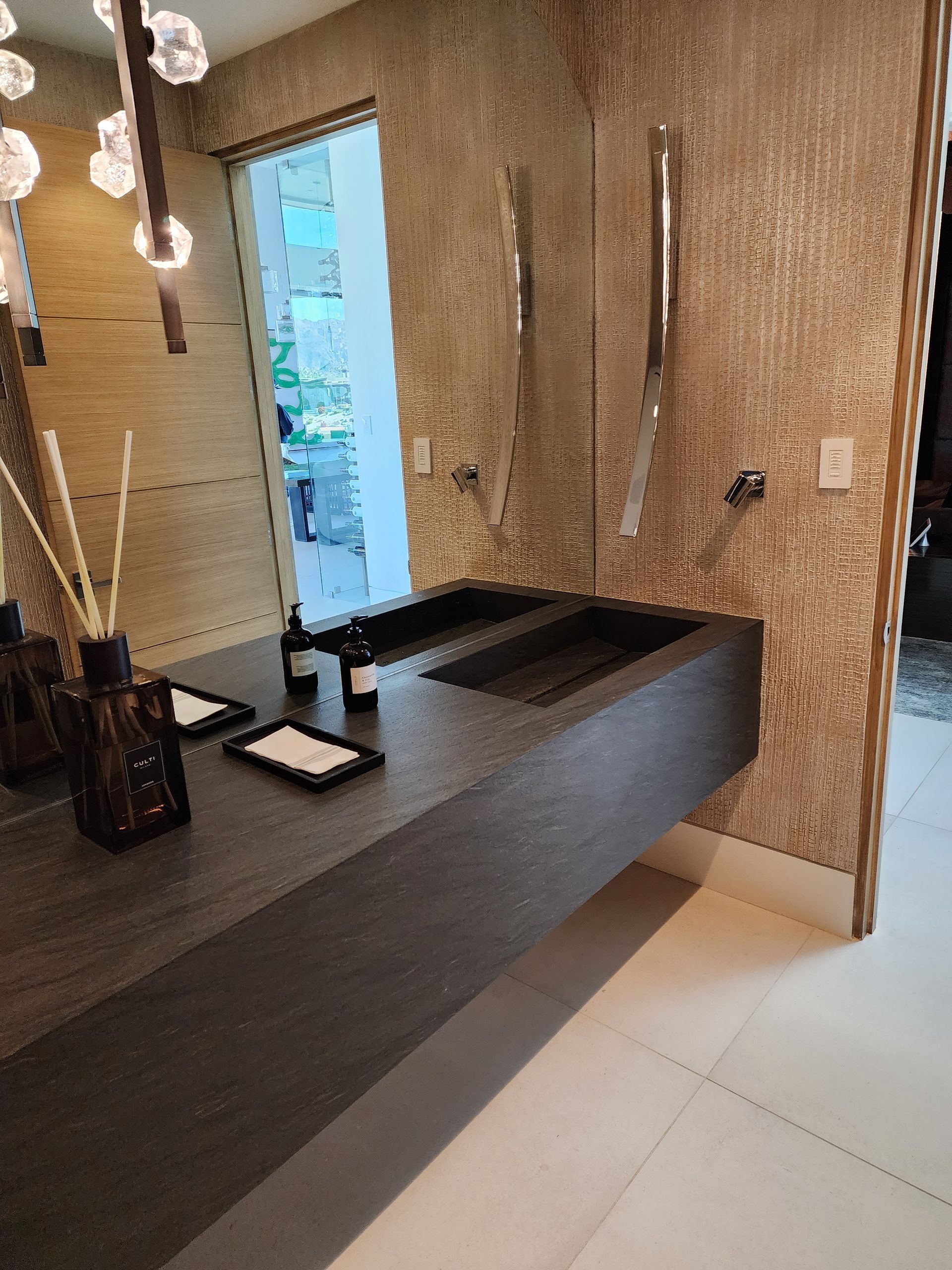 Modern bathroom with dark gray countertop, two sinks, and textured gold walls.