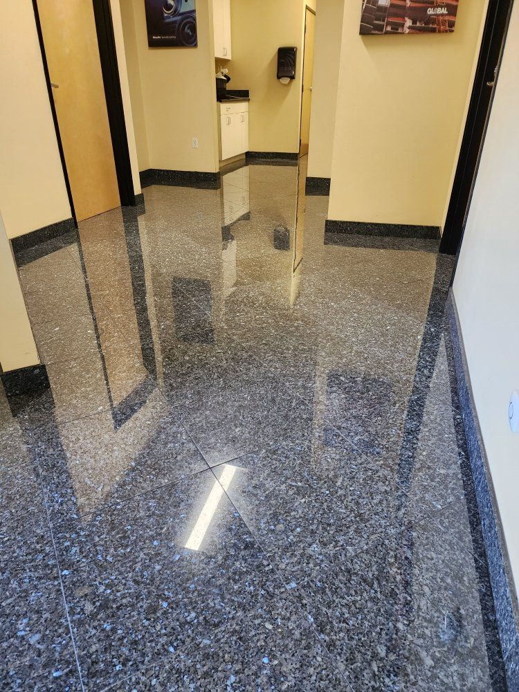 Polished speckled floor in a brightly lit hallway with beige walls, doors, and dark trim.