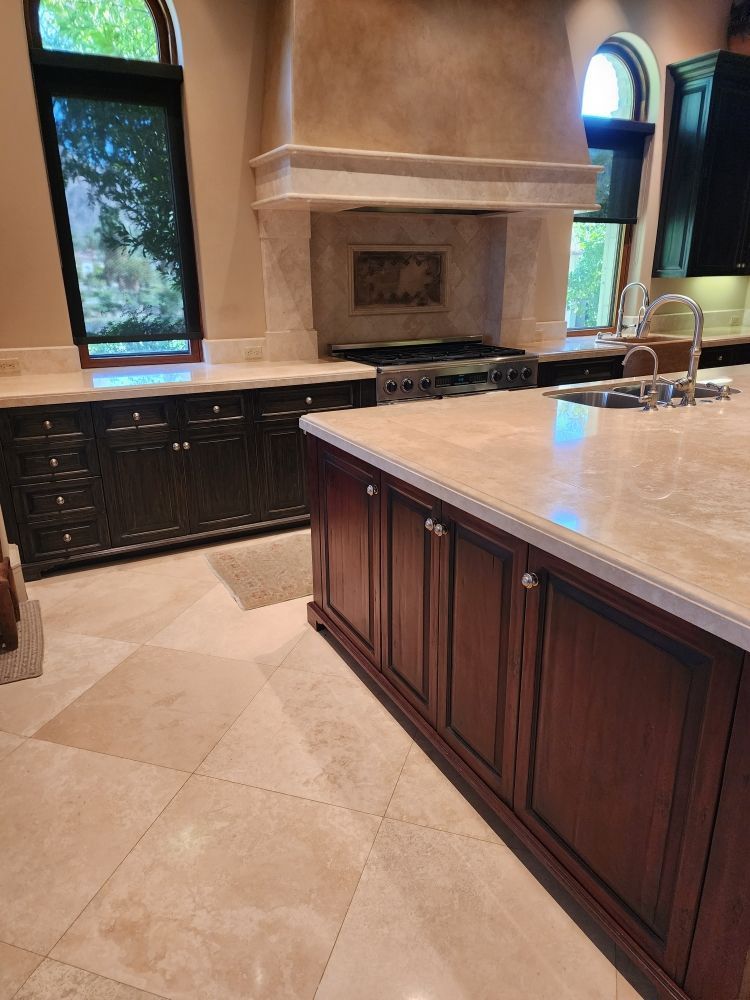 Kitchen with dark wood cabinets, light countertops, a range hood, and tiled floor.