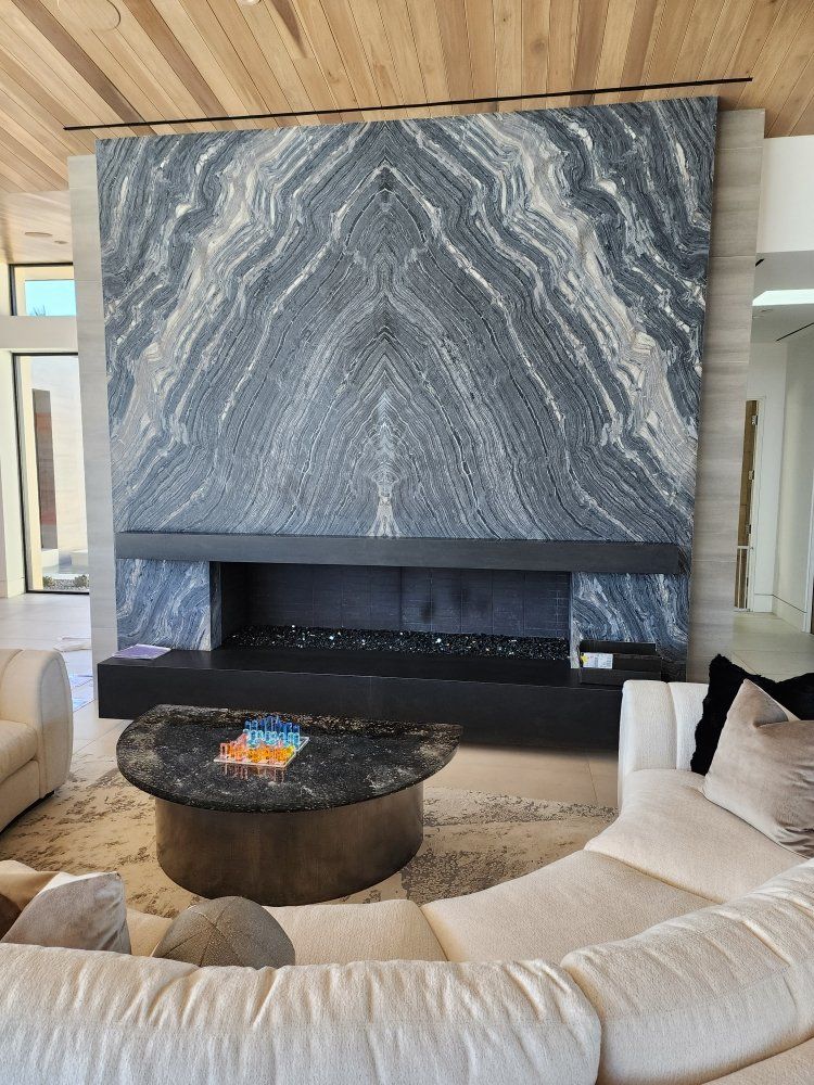 Large marble fireplace with black hearth, above a round coffee table and cream sofa.