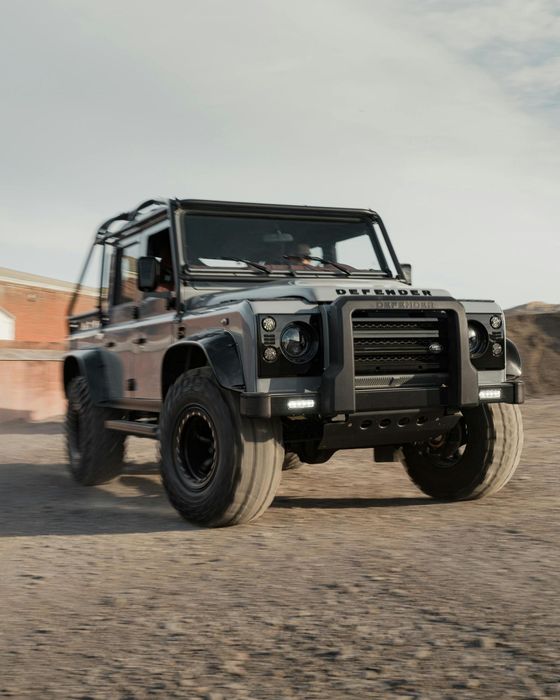 A black jeep is driving down a dirt road.