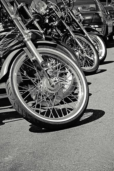 A black and white photo of a row of motorcycles parked next to each other.