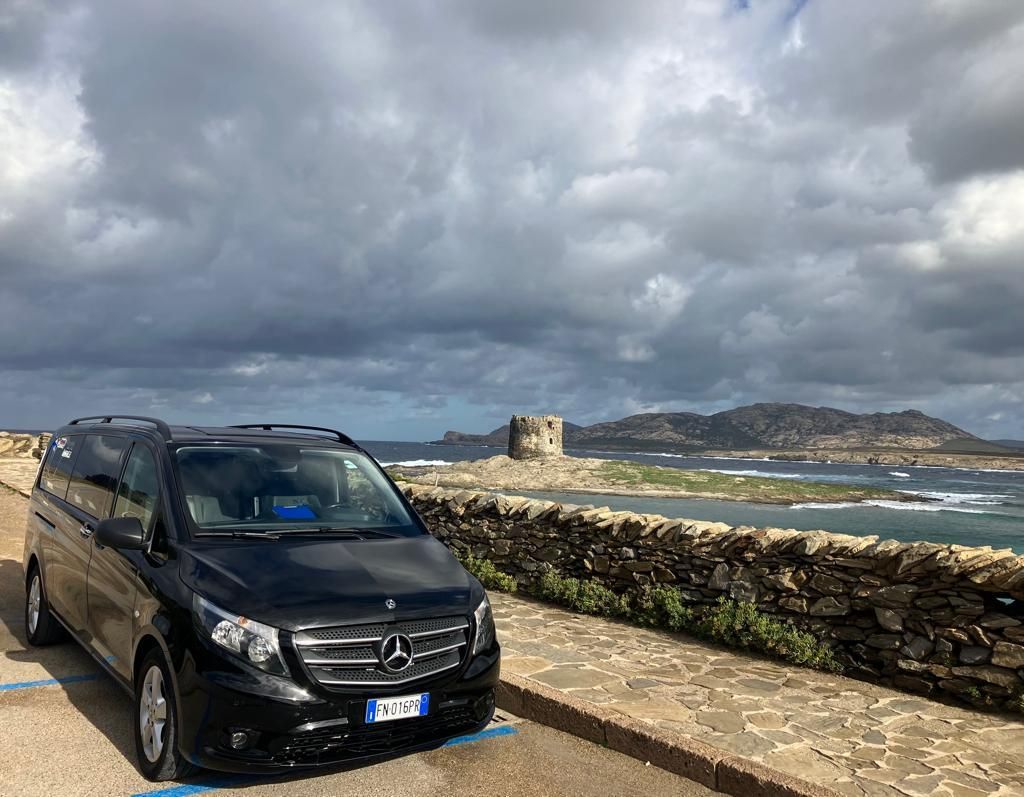 un'auto mercedes è parcheggiata accanto a un muro di pietra