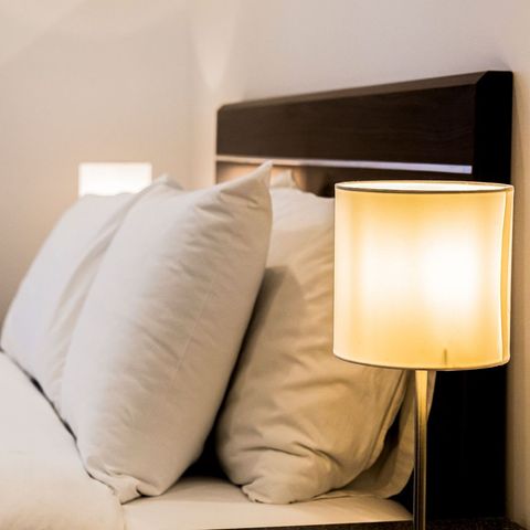 A bed with white sheets and pillows next to a lamp