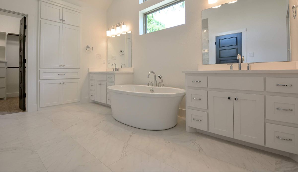 Spacious white bathroom with a freestanding tub, dual vanities, large mirrors, and cabinets.