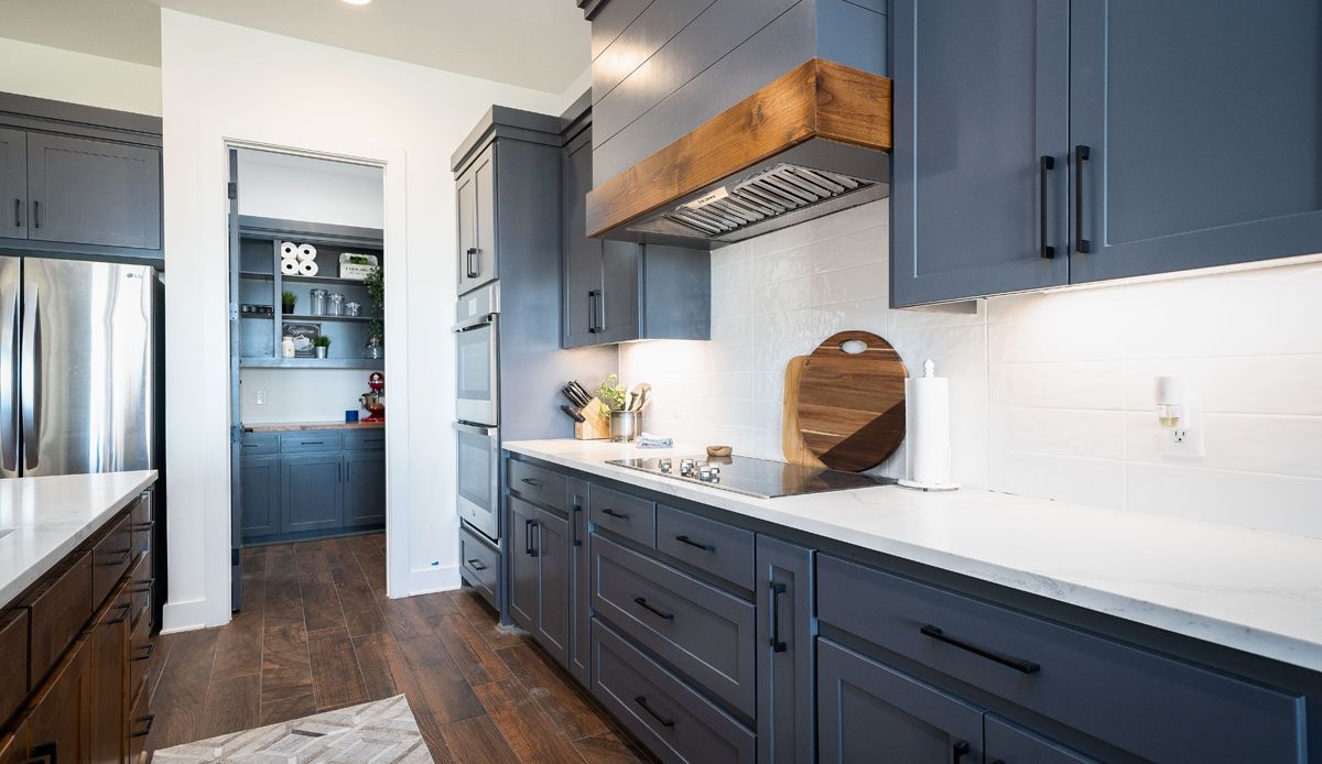 Modern kitchen with gray cabinets, white countertops, and wooden accents.