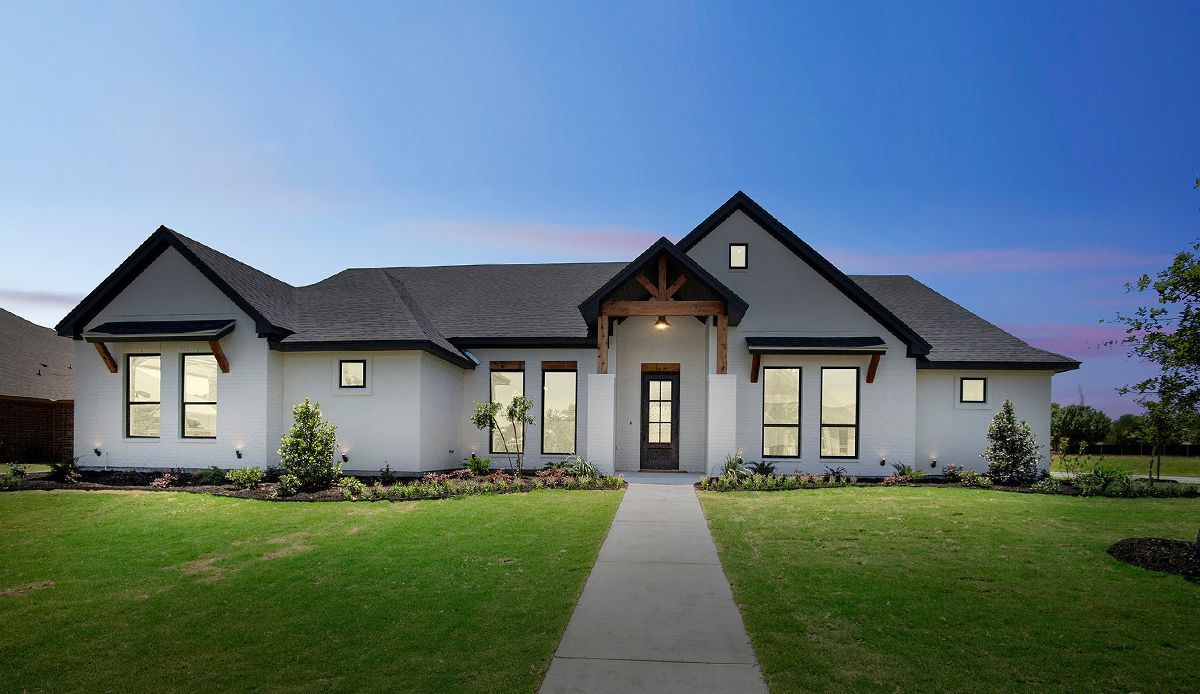 White house with black trim, green lawn, and a blue twilight sky.