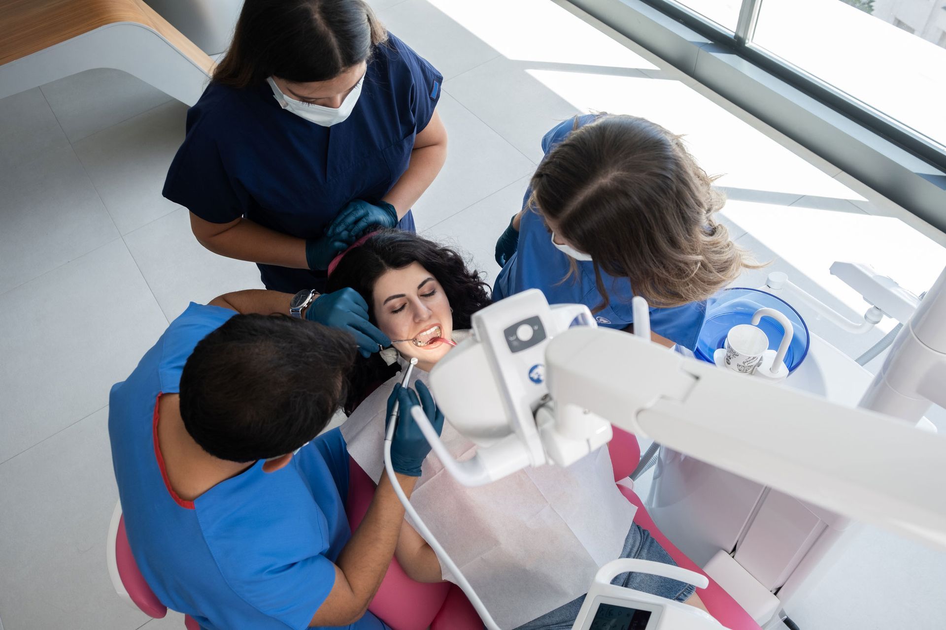 A group of dentists are examining a patient 's teeth in a dental office.