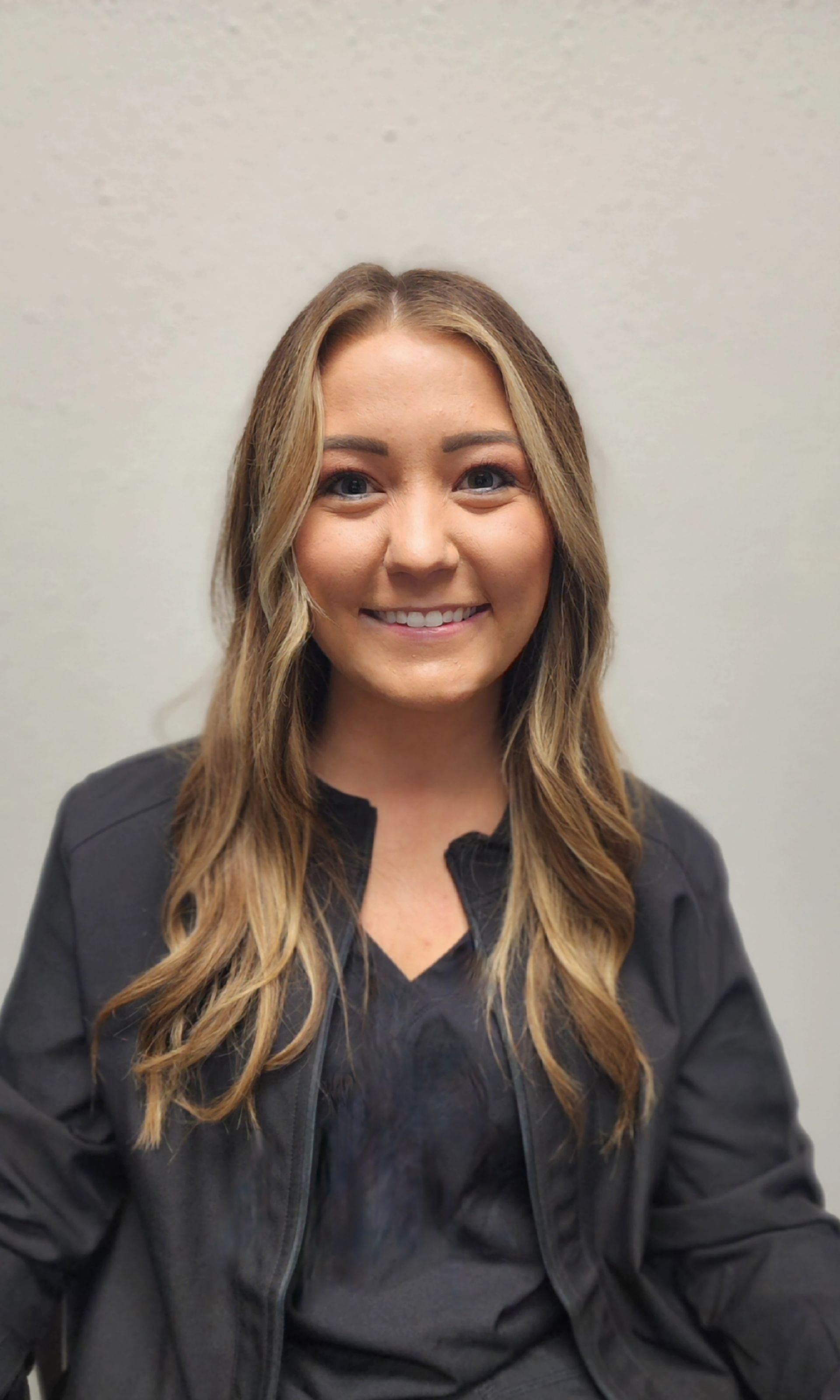 A woman wearing a black jacket and a black shirt is smiling for the camera.