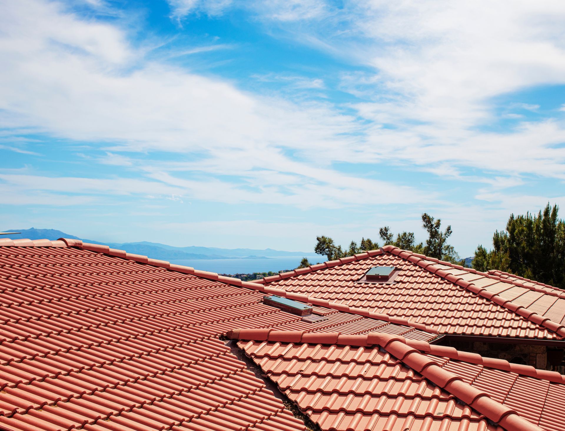 Red tile roof against a blue sky with clouds