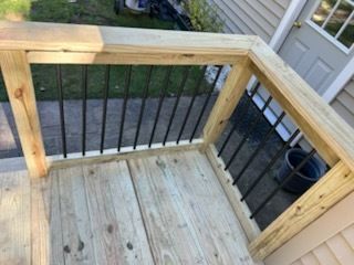 Wooden deck with black metal railing and a door in the background.