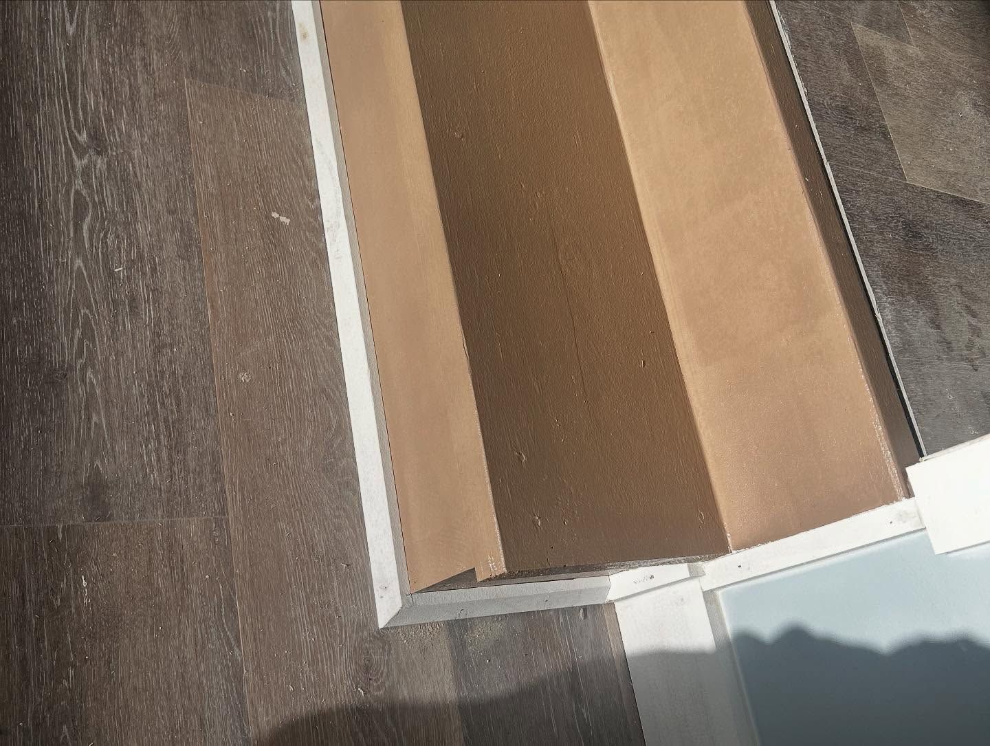 Close-up of floor samples in shades of brown and gray next to a white edge.