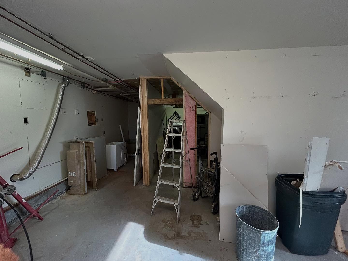 Garage under construction, unfinished walls, ladder, debris, and partial doorway.
