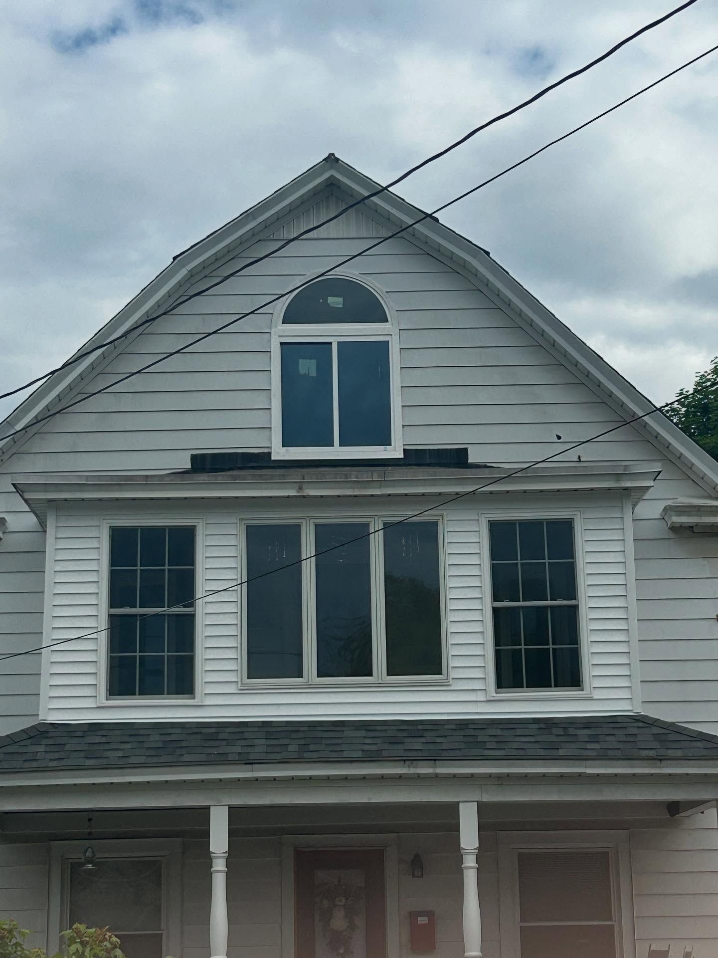 Two-story white house with a gable roof, windows on upper levels, and utility lines overhead.