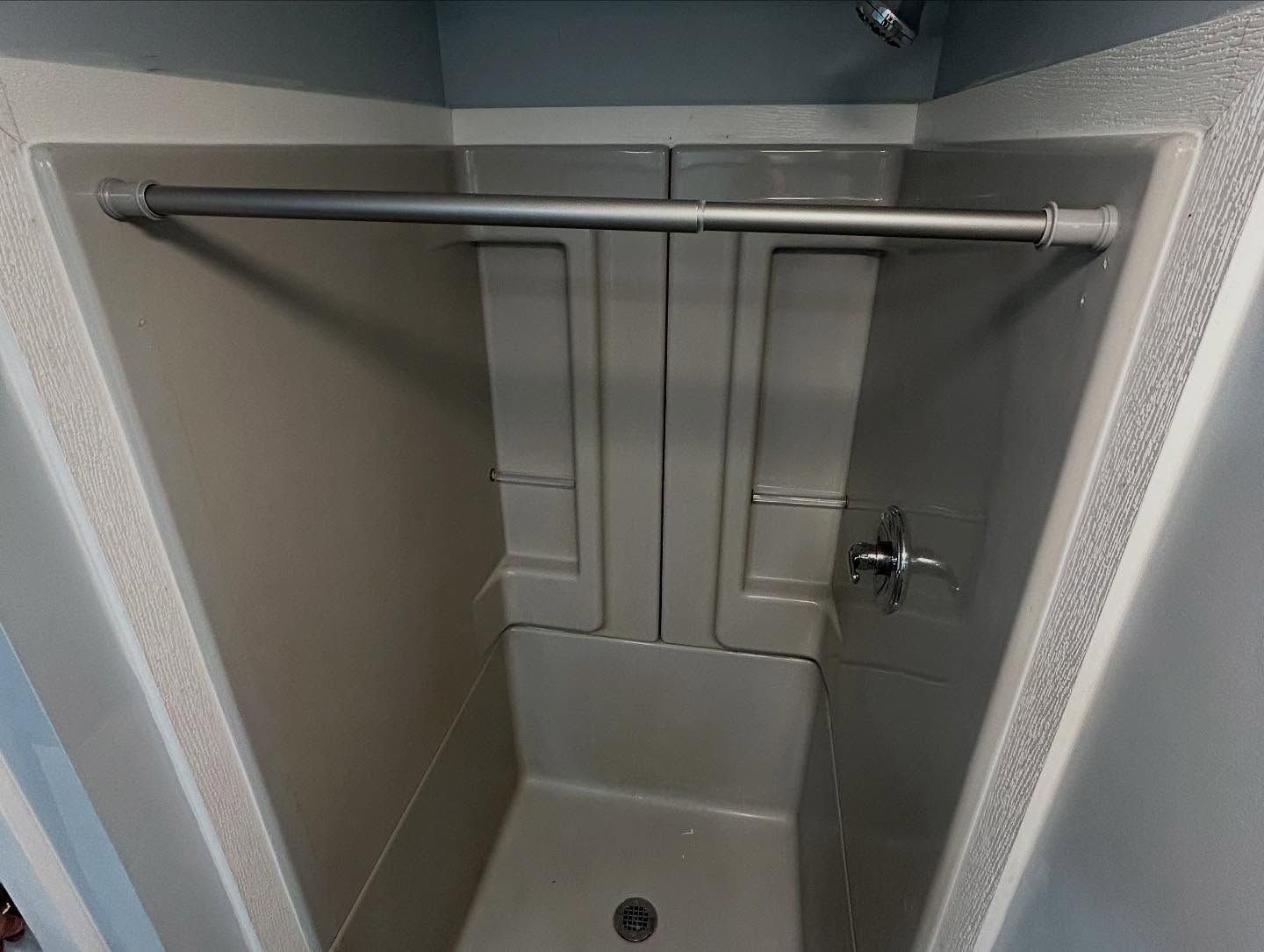 Gray shower stall with a curtain rod installed.
