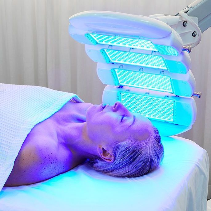 A woman is laying on a bed under a blue light.