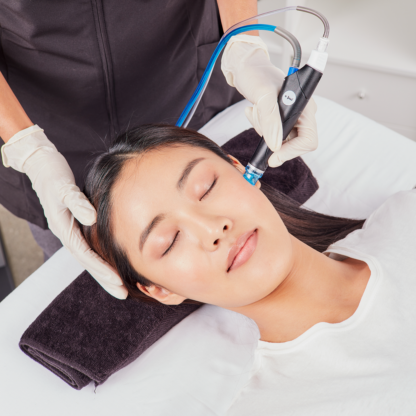 A woman is laying on a bed getting a facial treatment