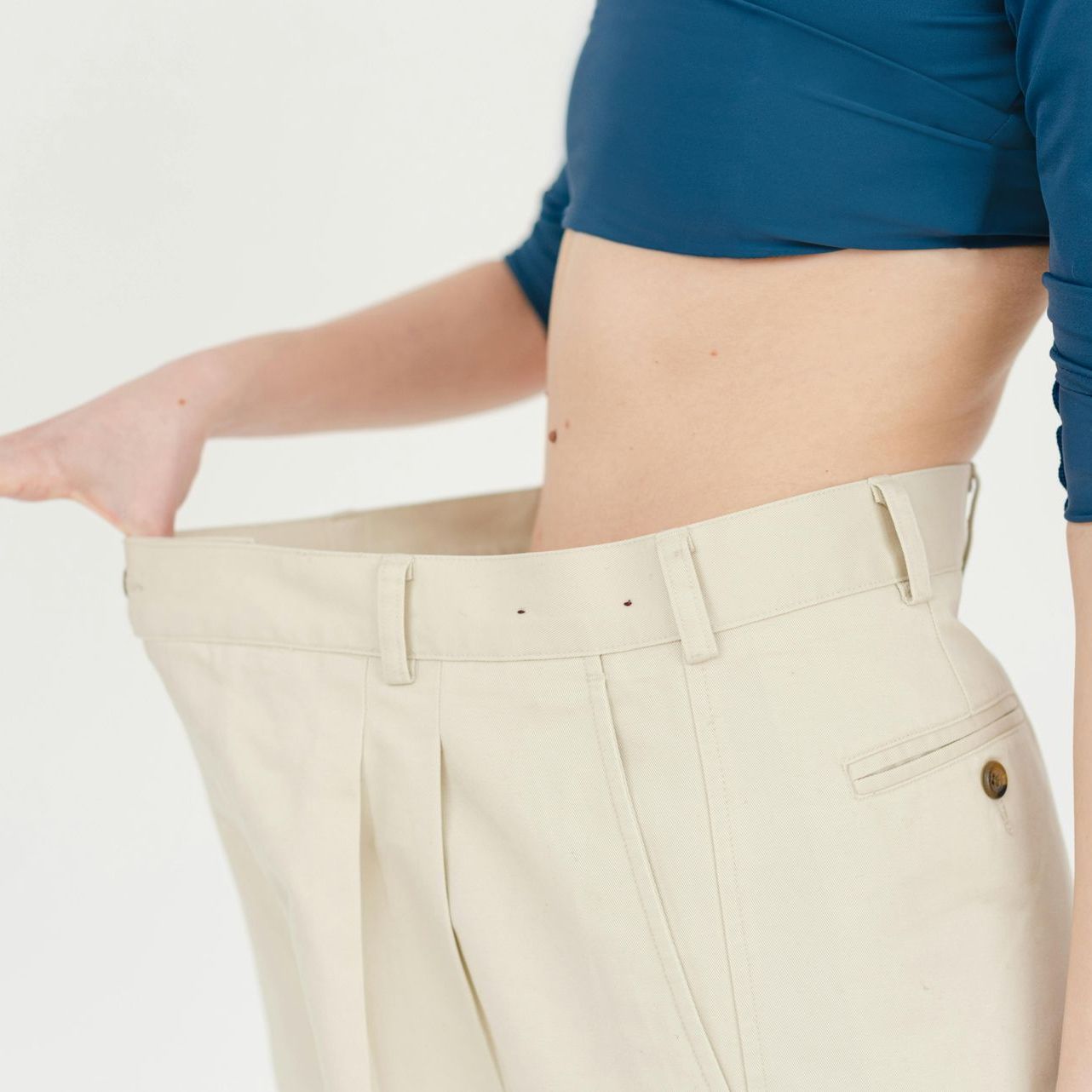 A woman wearing a blue crop top and white pants has lost weight