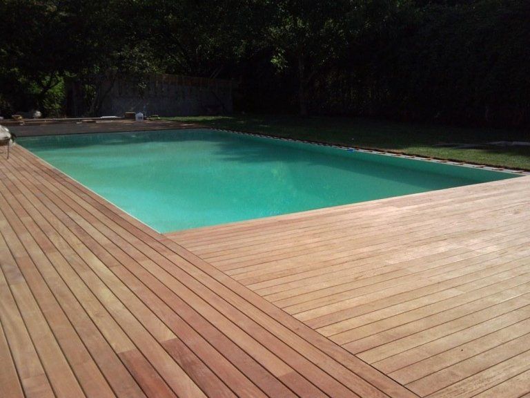 una piscina e attorno una pavimentazione in legno