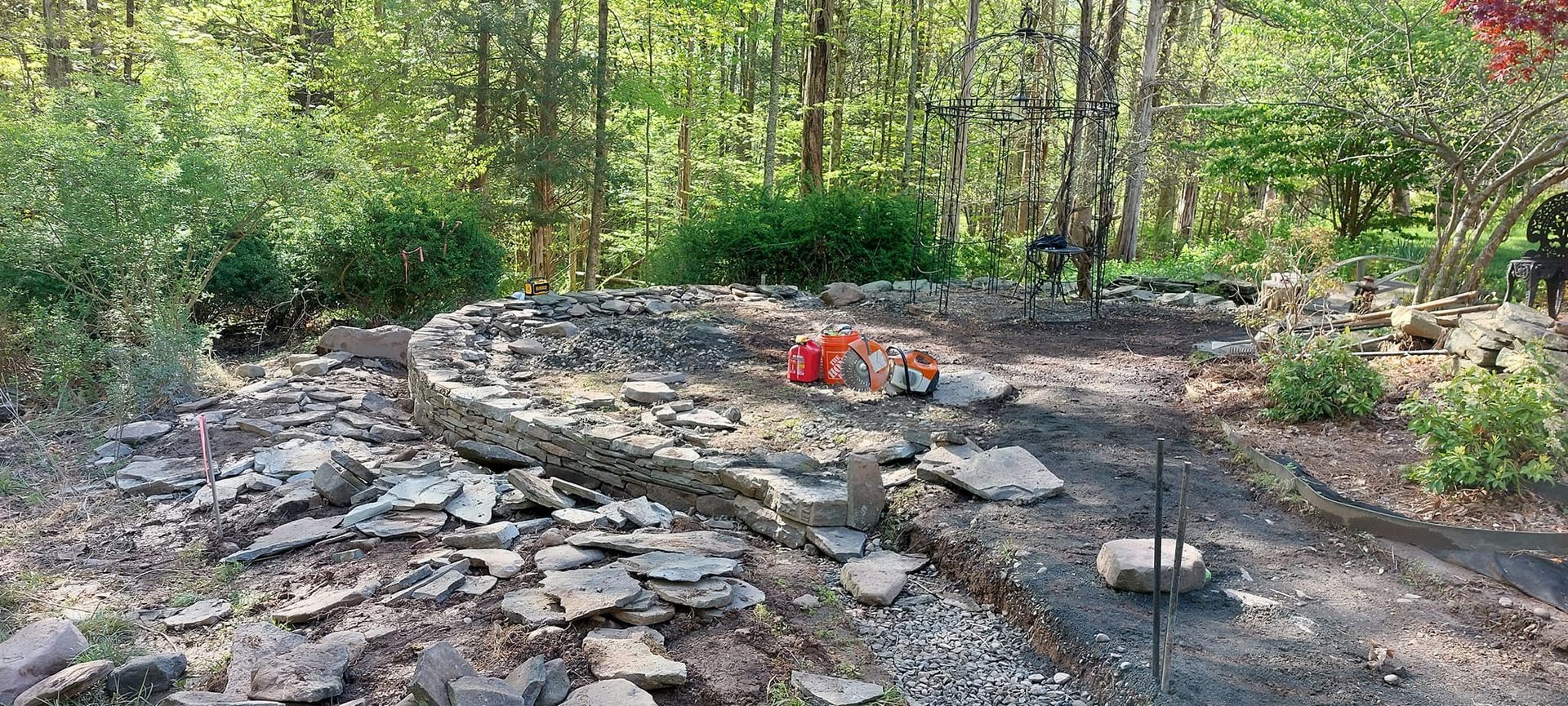 A work site in a forest with rock and brick pieces scattered on the ground.