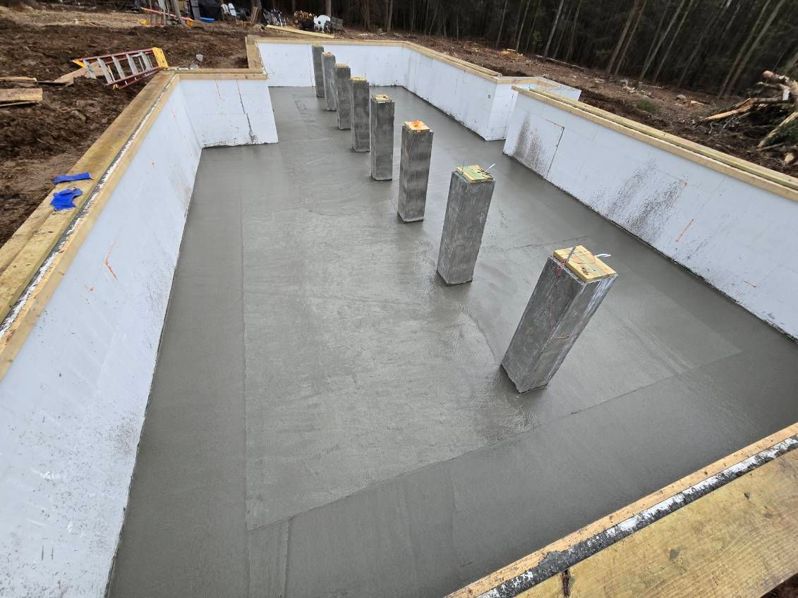 Concrete foundation with gray pillars inside, ready for construction.