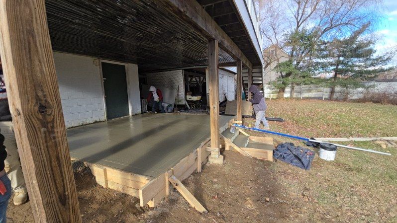 Concrete being poured on a porch, with workers present. Outdoors, overcast.