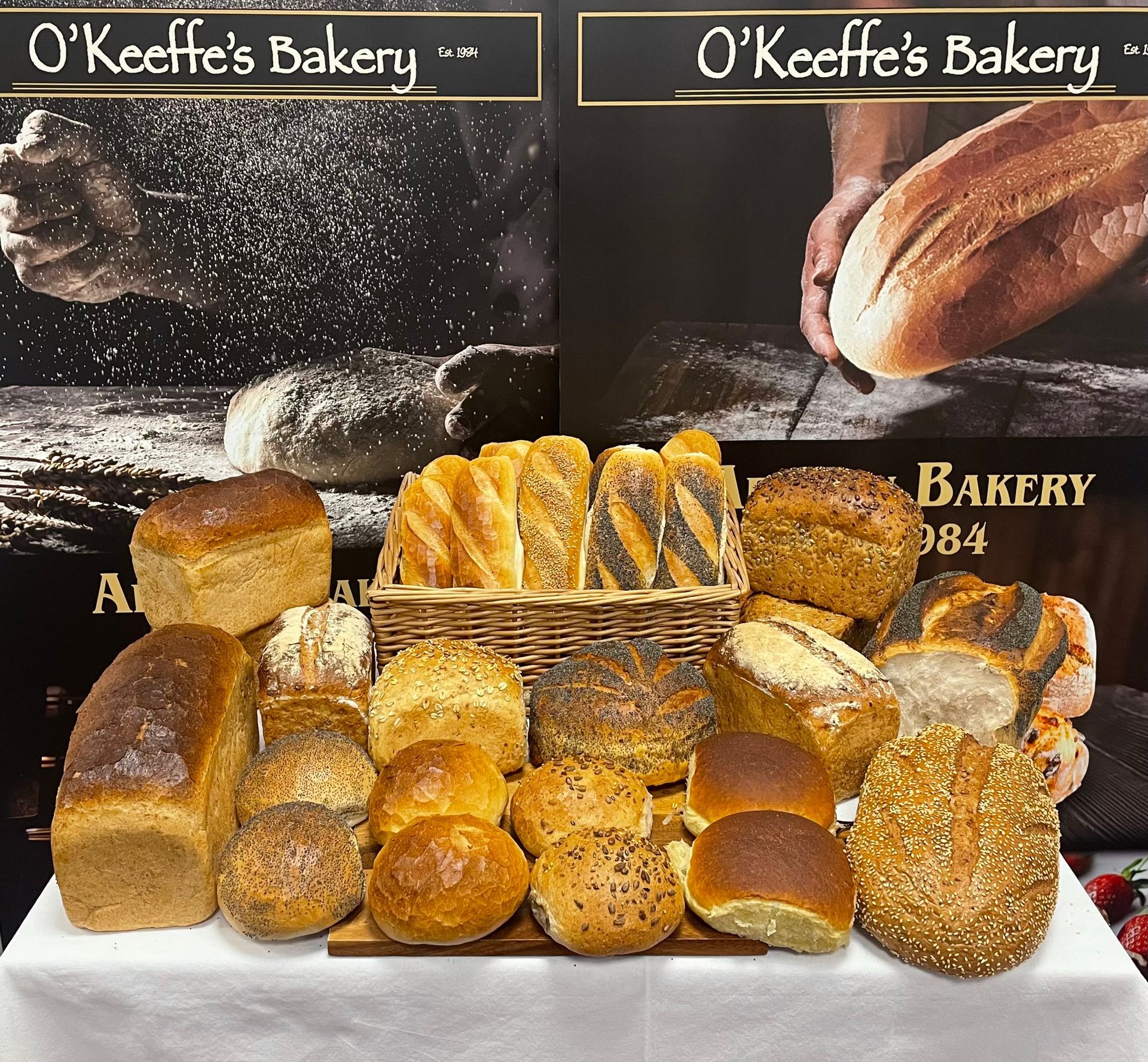A basket of bread sits on a table in front of a sign for o keeffe 's bakery
