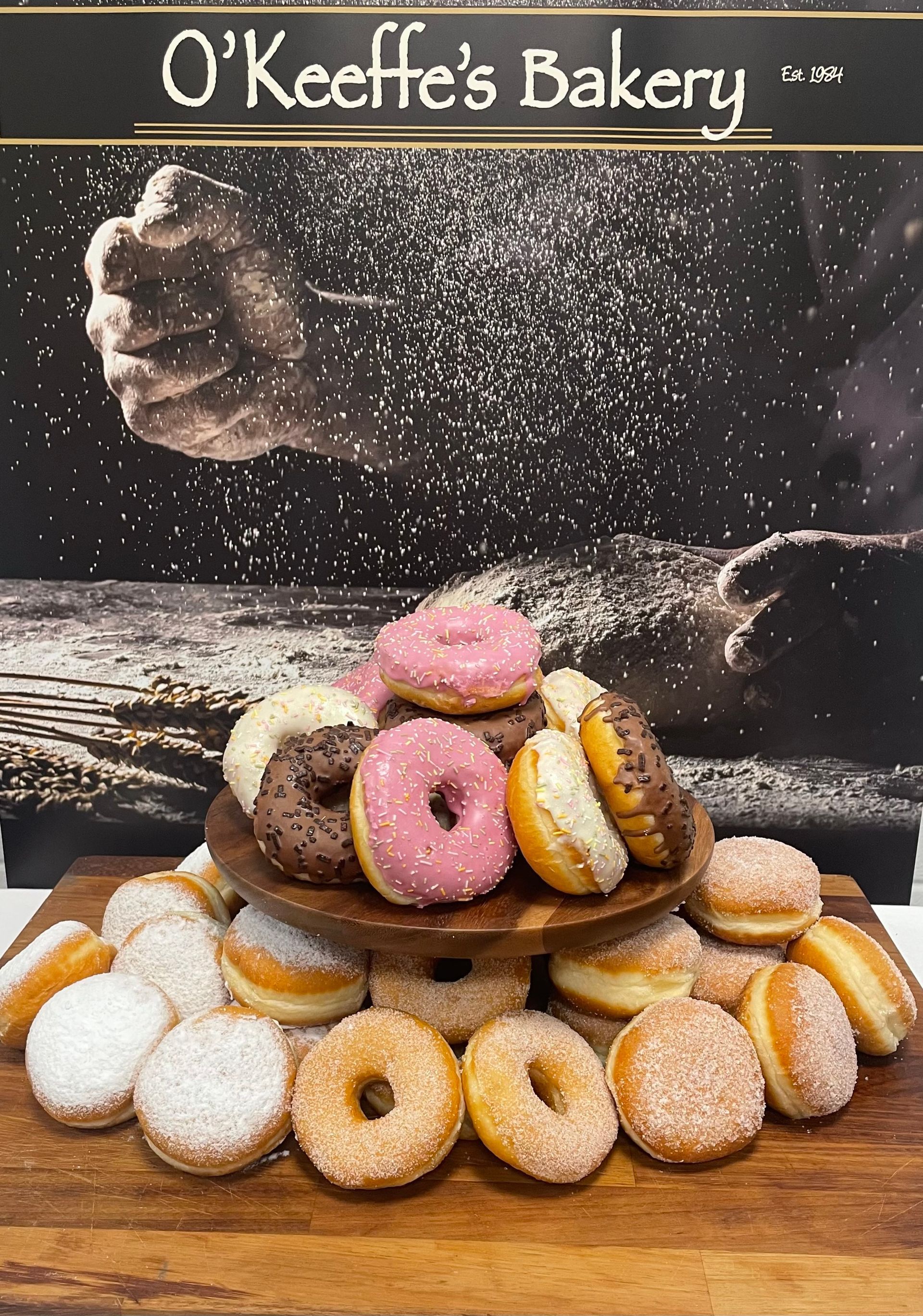 A bunch of donuts are stacked on top of each other on a wooden table.