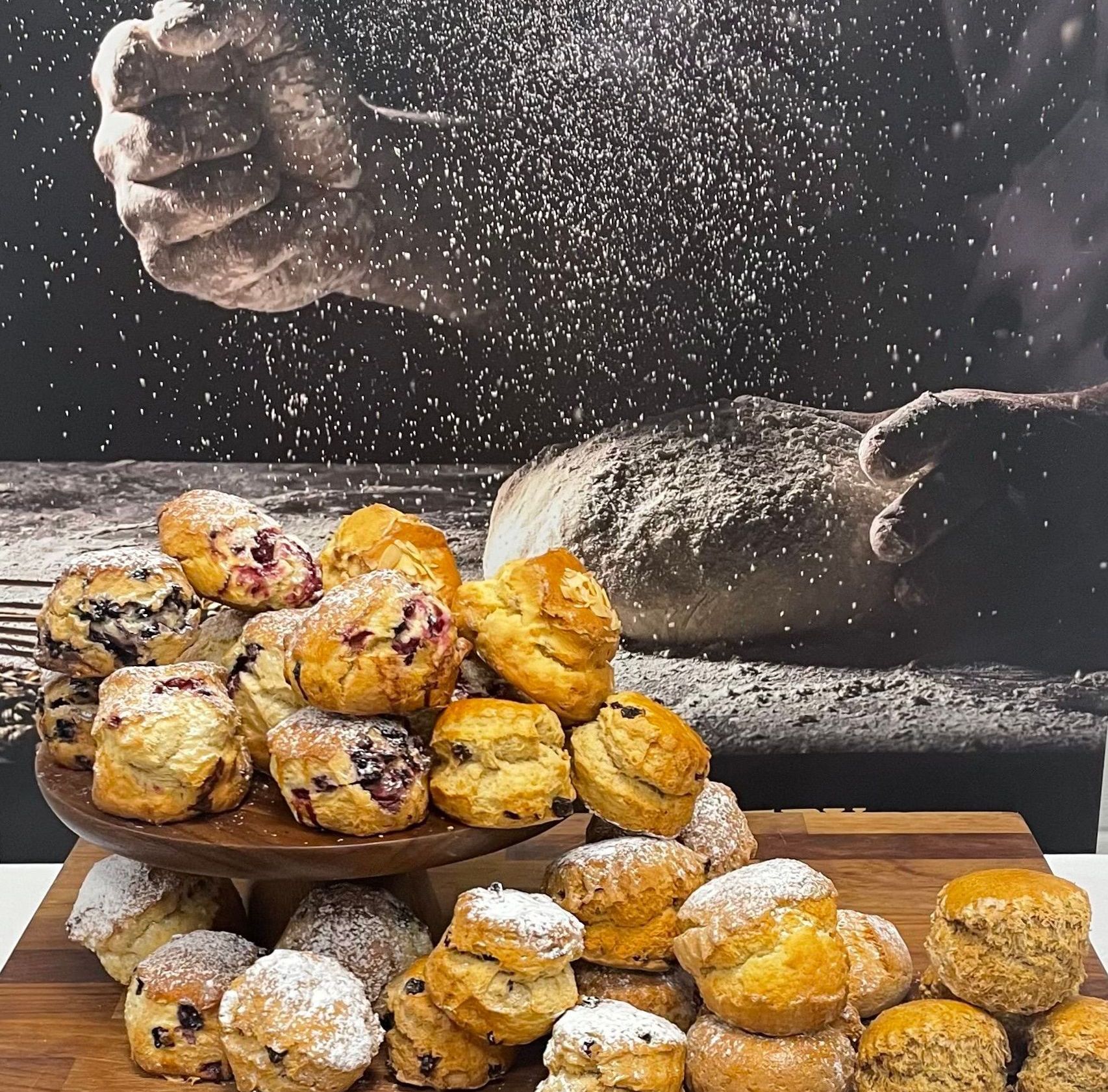 A bunch of pastries on a wooden table with powdered sugar on them