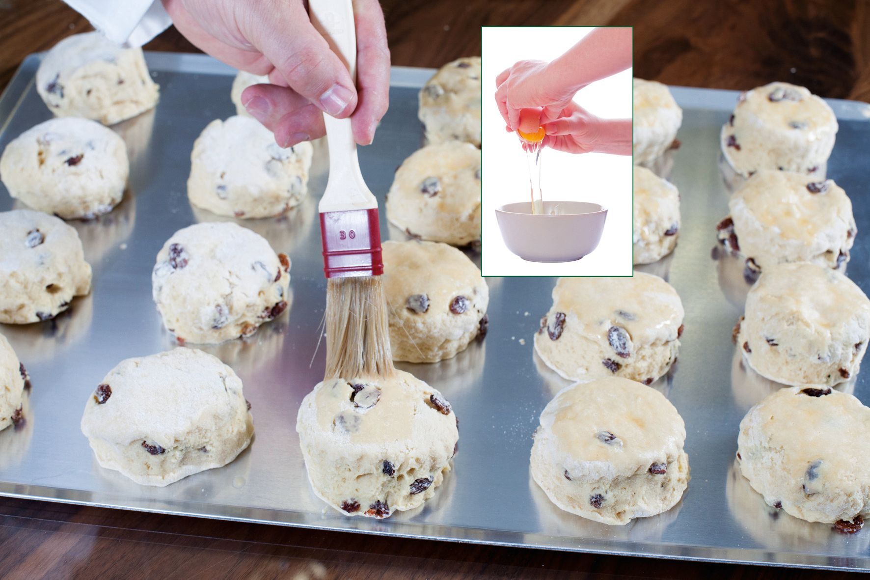 A tray of scones being brushed with powdered sugar