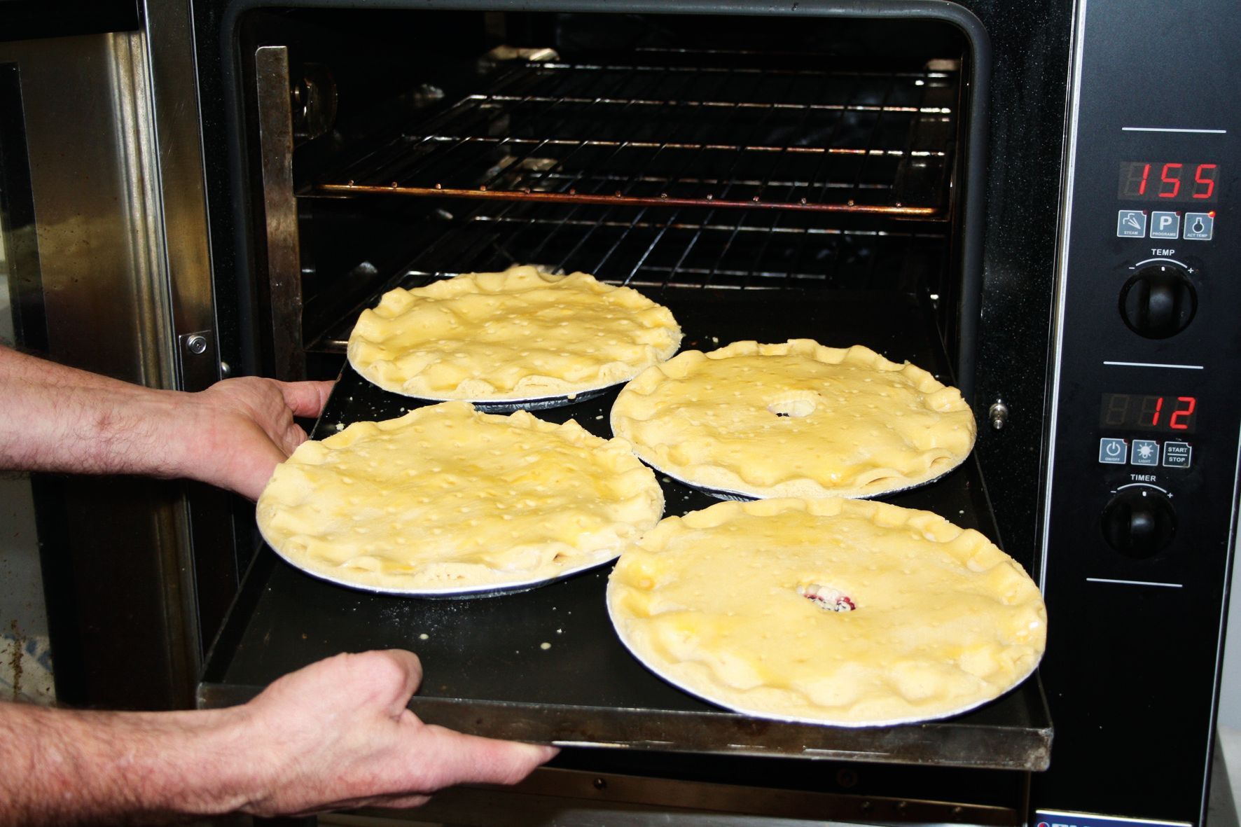 Four pies are being taken out of an oven that says 1758