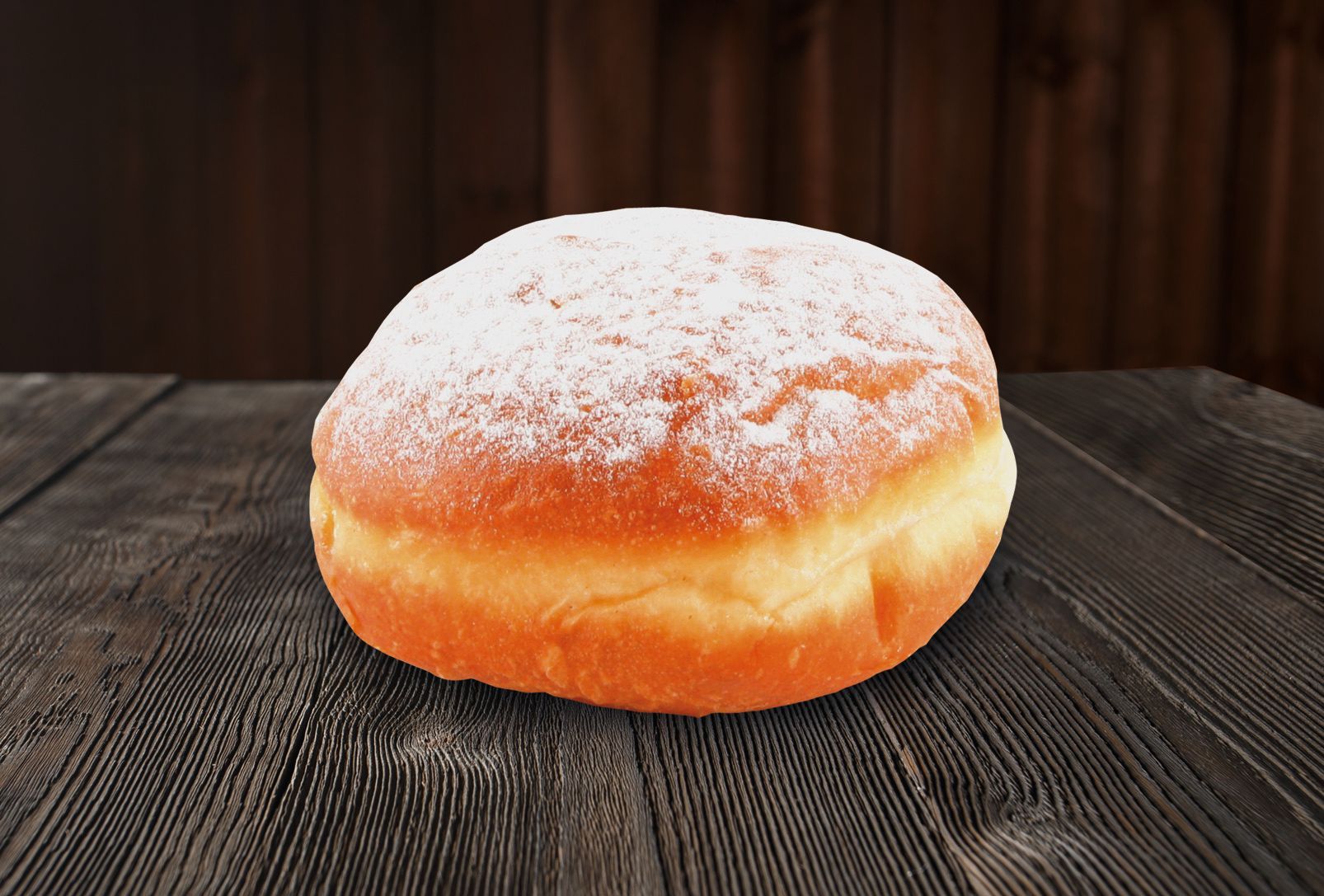 A donut with powdered sugar on top is sitting on a wooden table.